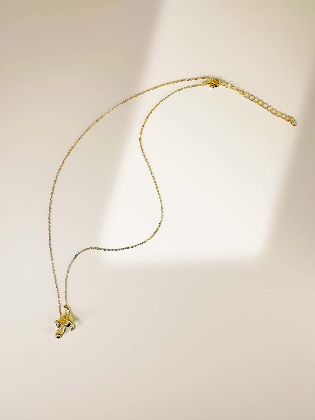 Full flat lay view of the 18K gold cat pendant necklace showing the fine cable chain and lobster clasp closure