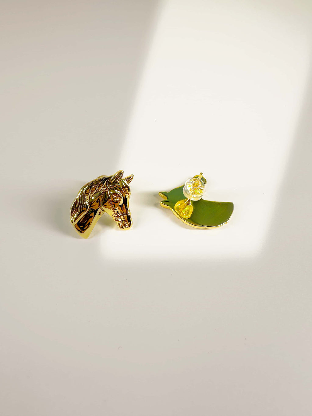 Detailed view of 18K gold horse earrings showing the sculpted front and secure backing post