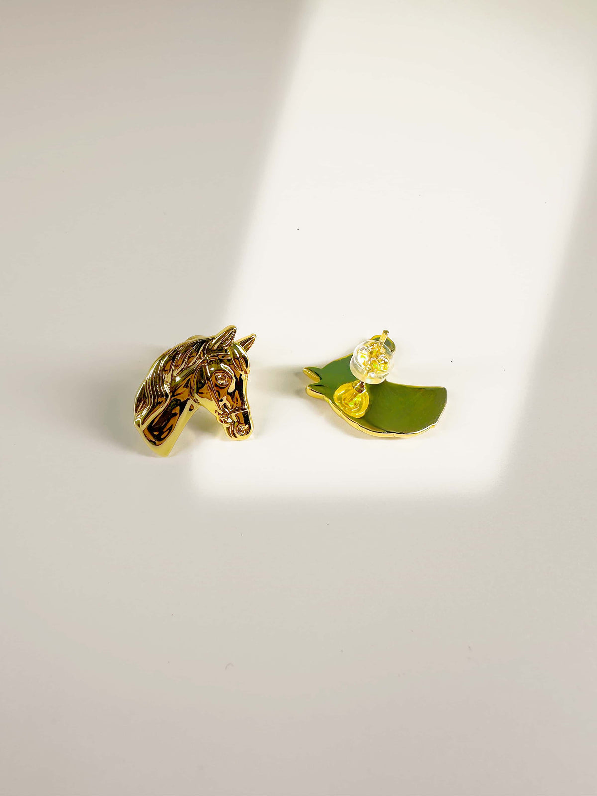 Detailed view of 18K gold horse earrings showing the sculpted front and secure backing post
