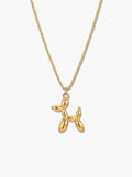 A close-up front view of an 18K gold plated balloon dog pendant necklace suspended from a delicate gold chain against a clean, light grey background