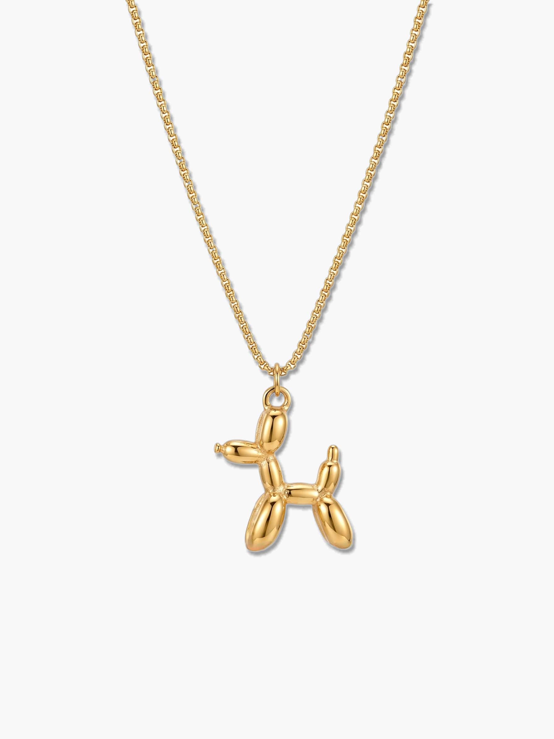 A close-up front view of an 18K gold plated balloon dog pendant necklace suspended from a delicate gold chain against a clean, light grey background