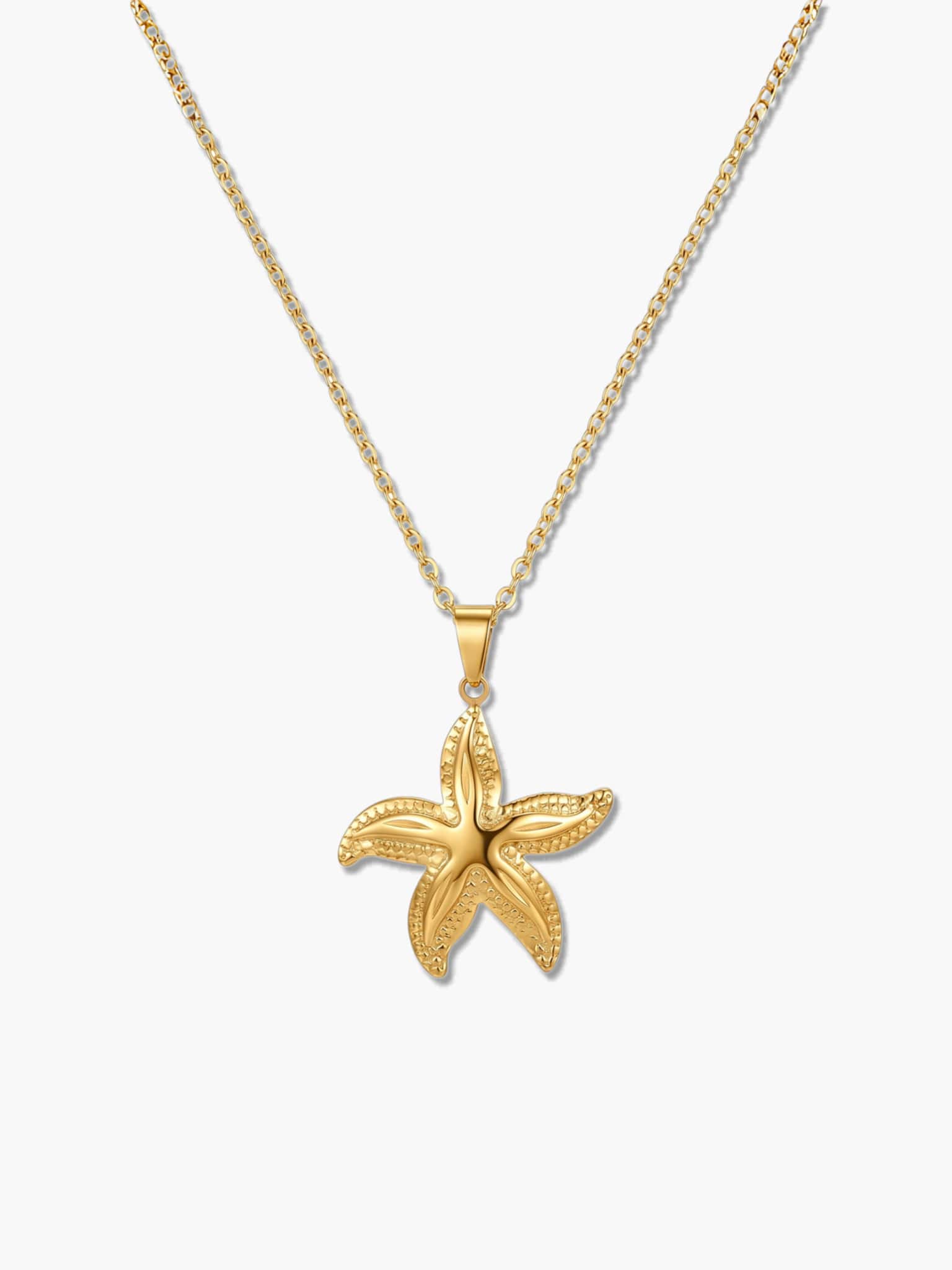 A detailed product shot of an 18K gold starfish necklace with an intricately textured star pendant on a delicate gold chain over a white background
