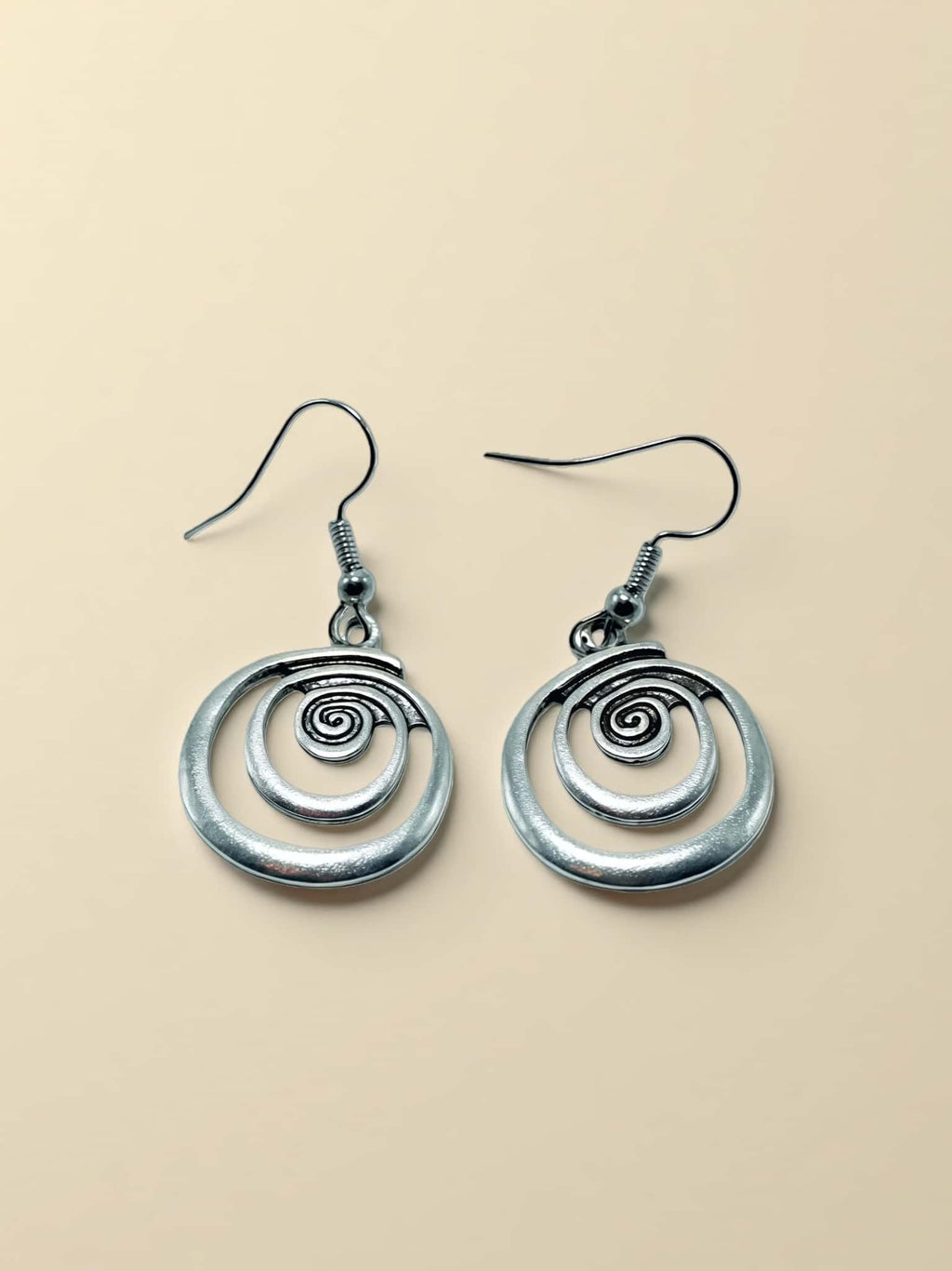 Pair of silver spiral earrings on a beige background