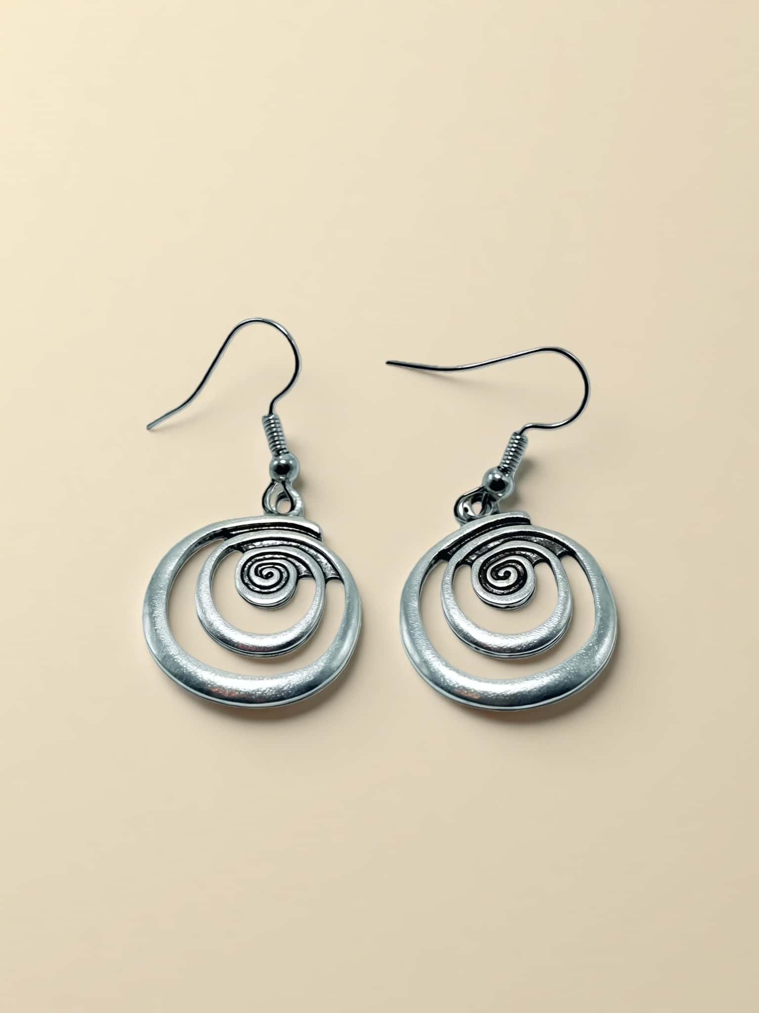 Pair of silver spiral earrings on a beige background