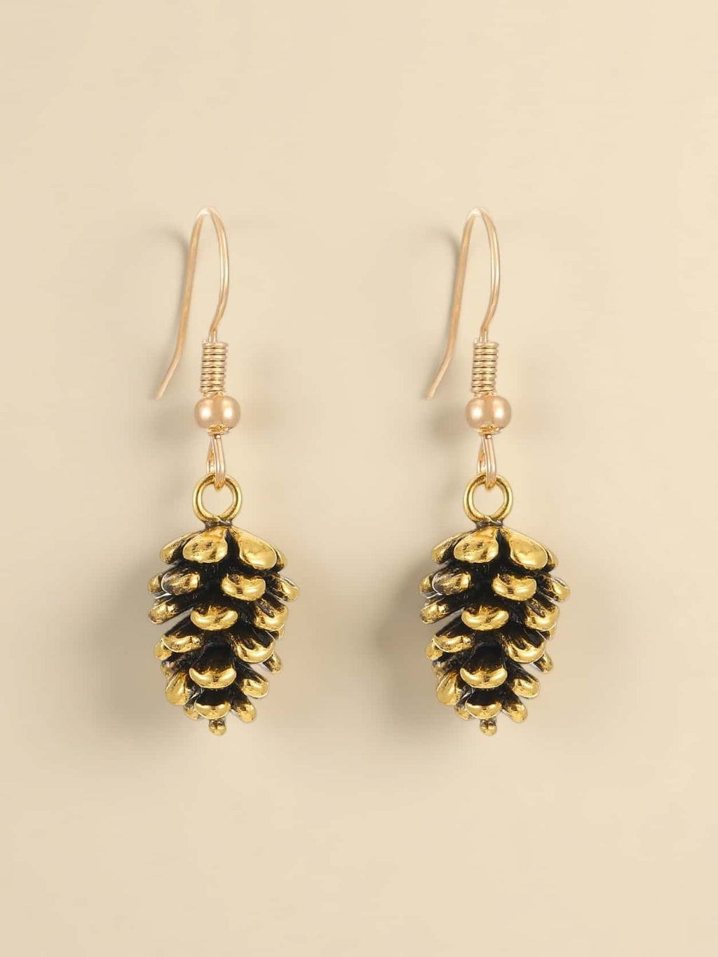 Pine cone-shaped earrings with gold and black finish on a beige background
