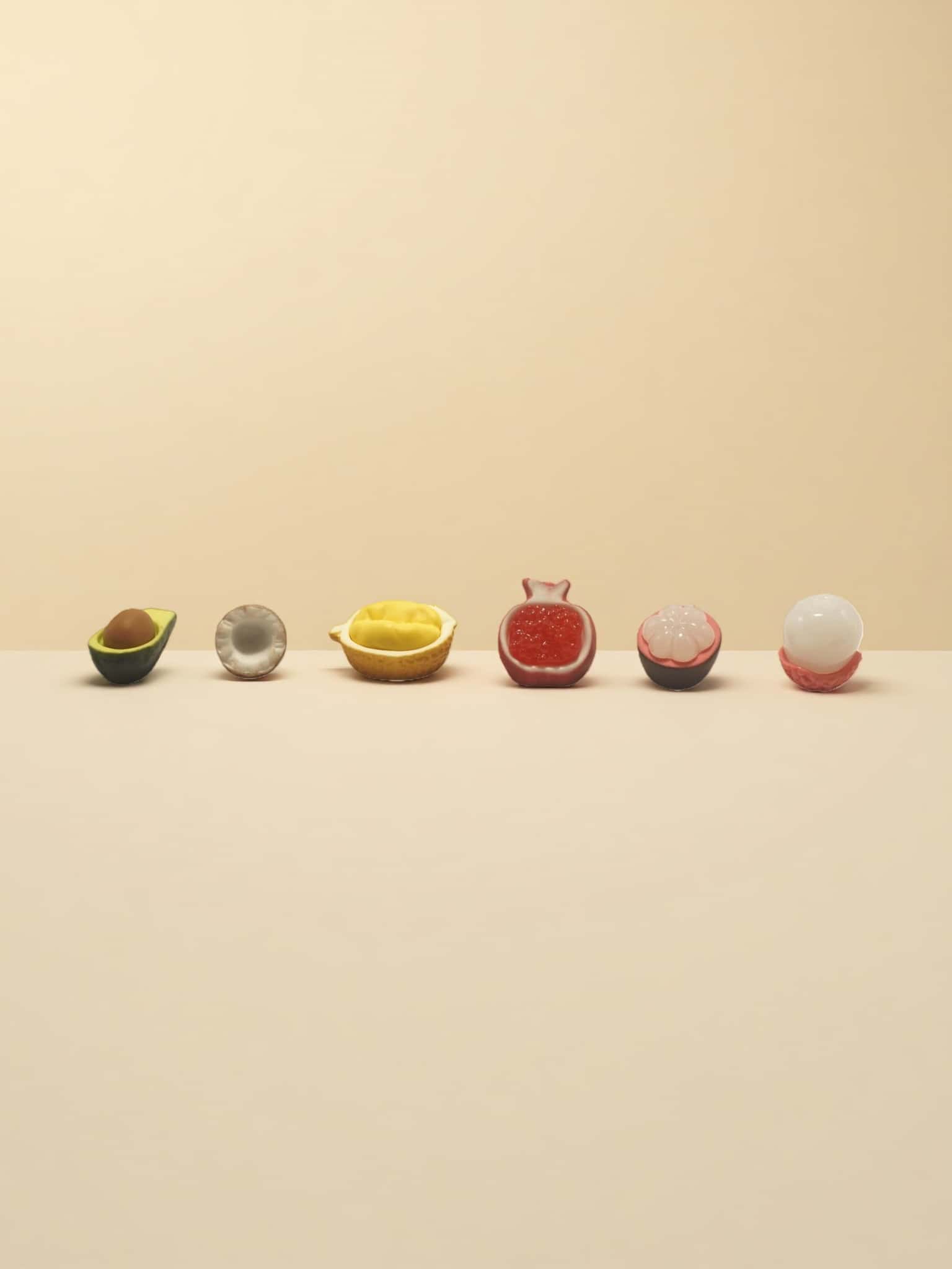 Row of colorful fruit-shaped candies on a beige background