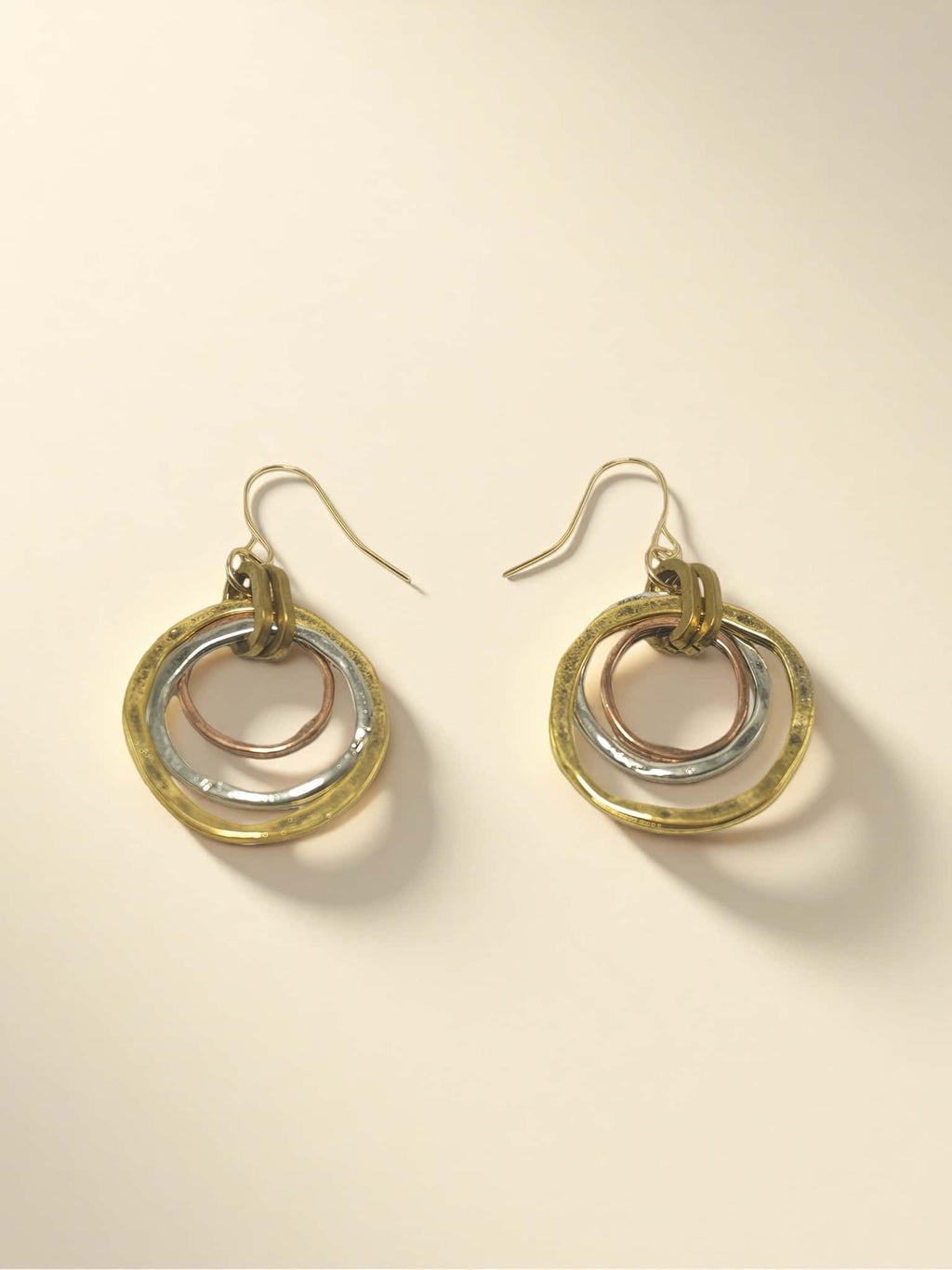 Pair of gold and silver hoop earrings on a beige background