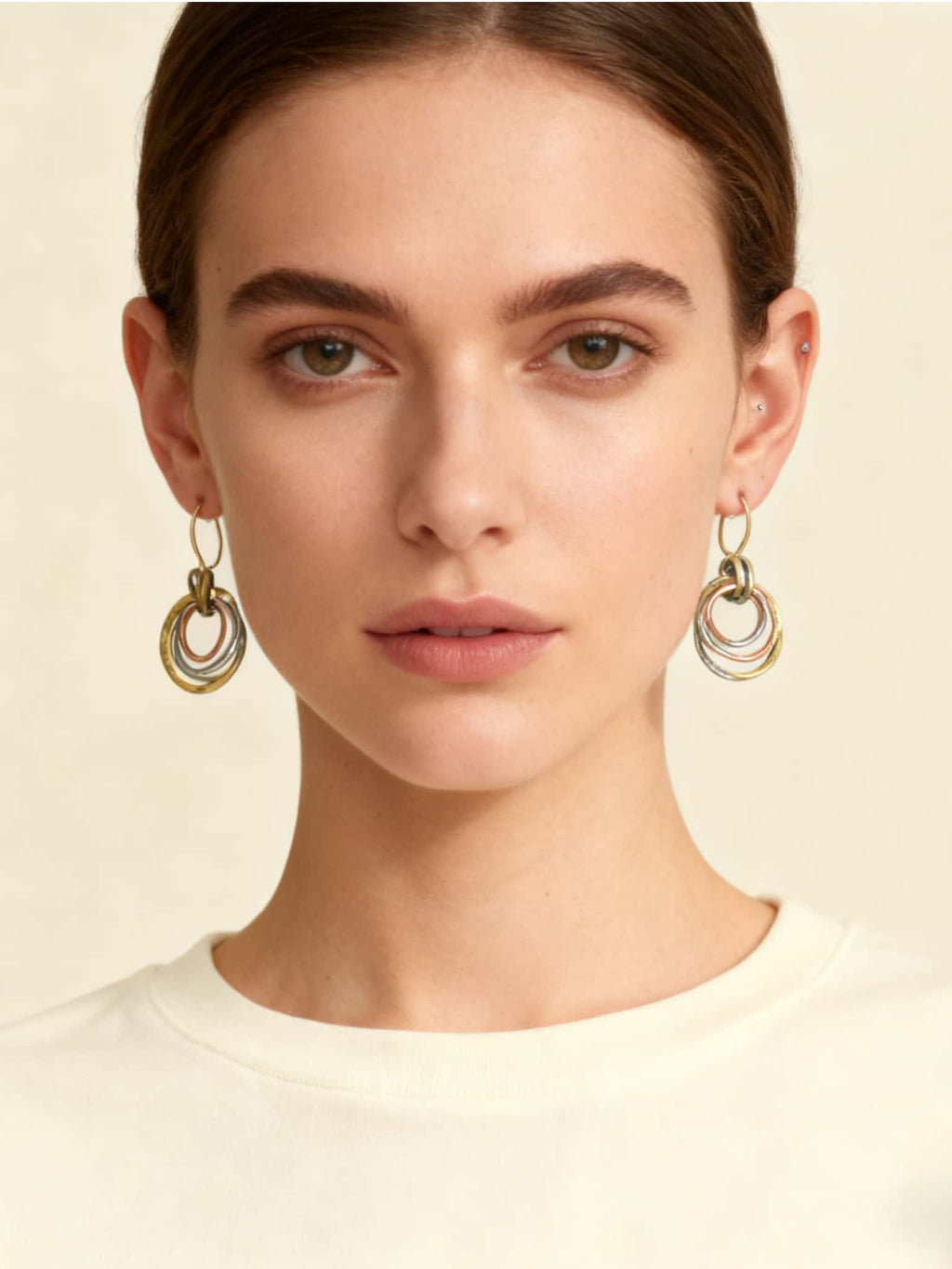 Woman wearing gold hoop earrings against a neutral background