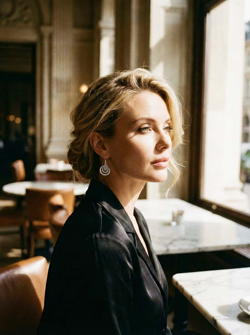 Woman sitting in a cafe with sunlight streaming through the window