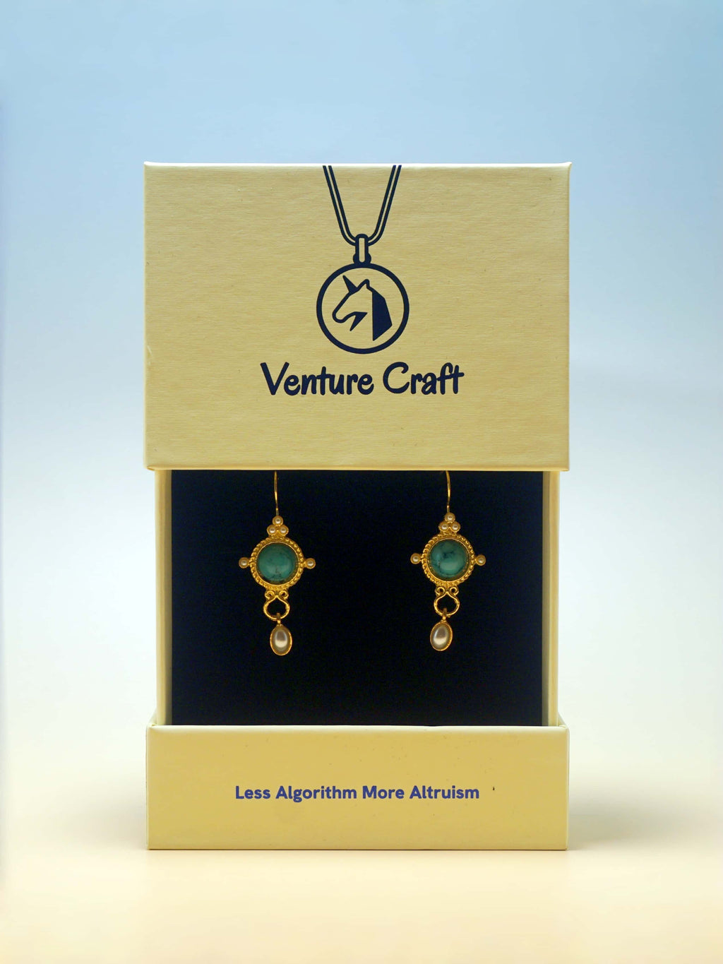 Gold earrings with green stones on a Venture Craft branded box.