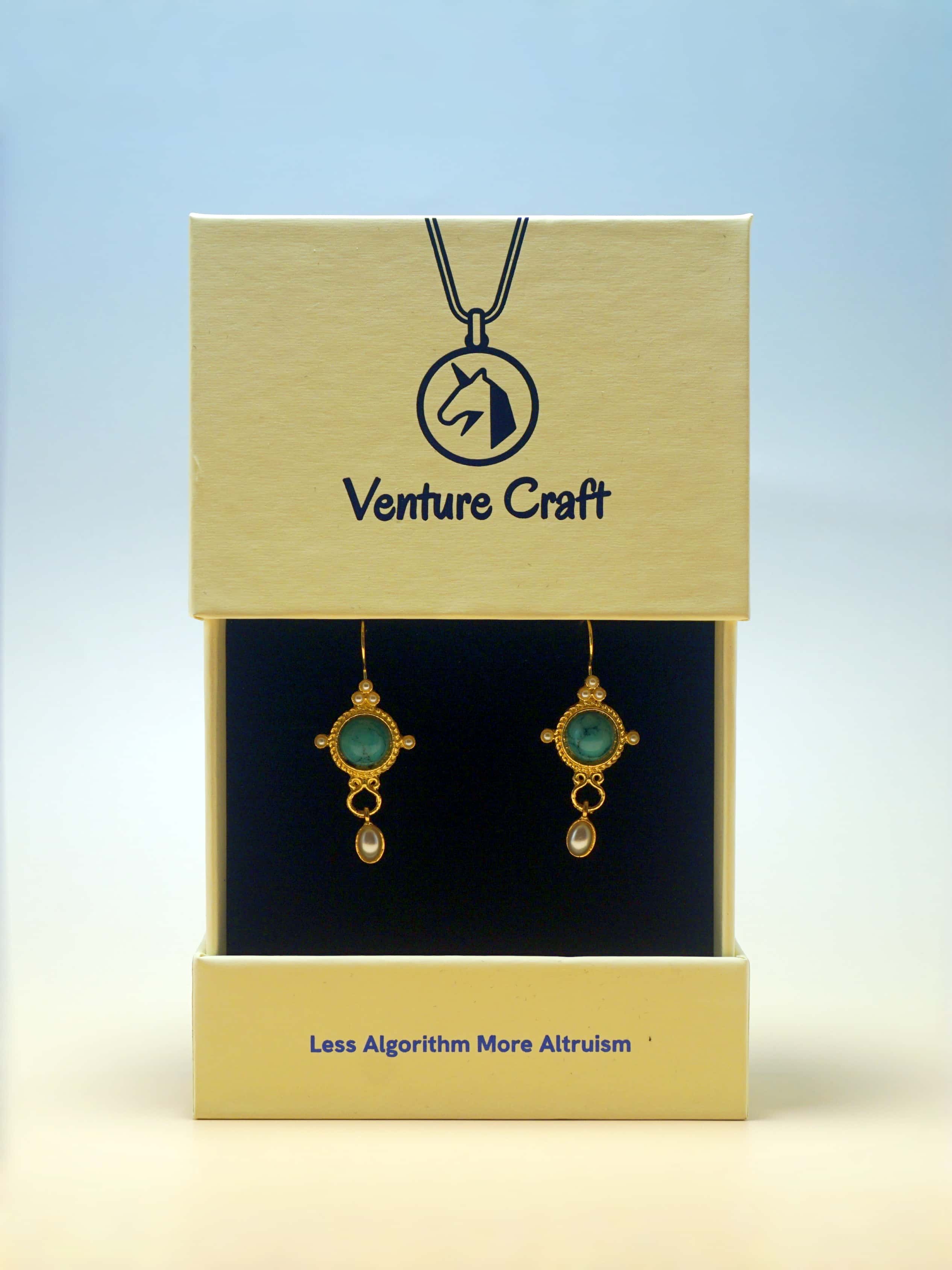 Gold earrings with green stones on a Venture Craft branded box.