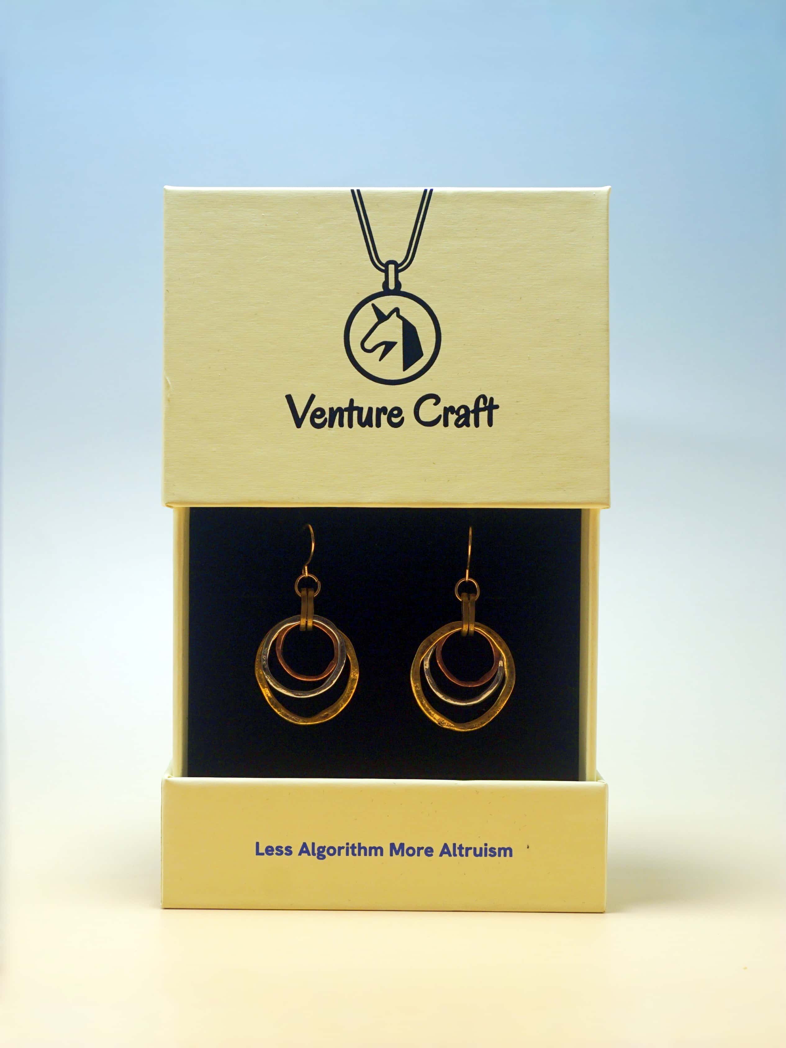 Jewelry set with necklace and earrings in Venture Craft packaging on a light blue background
