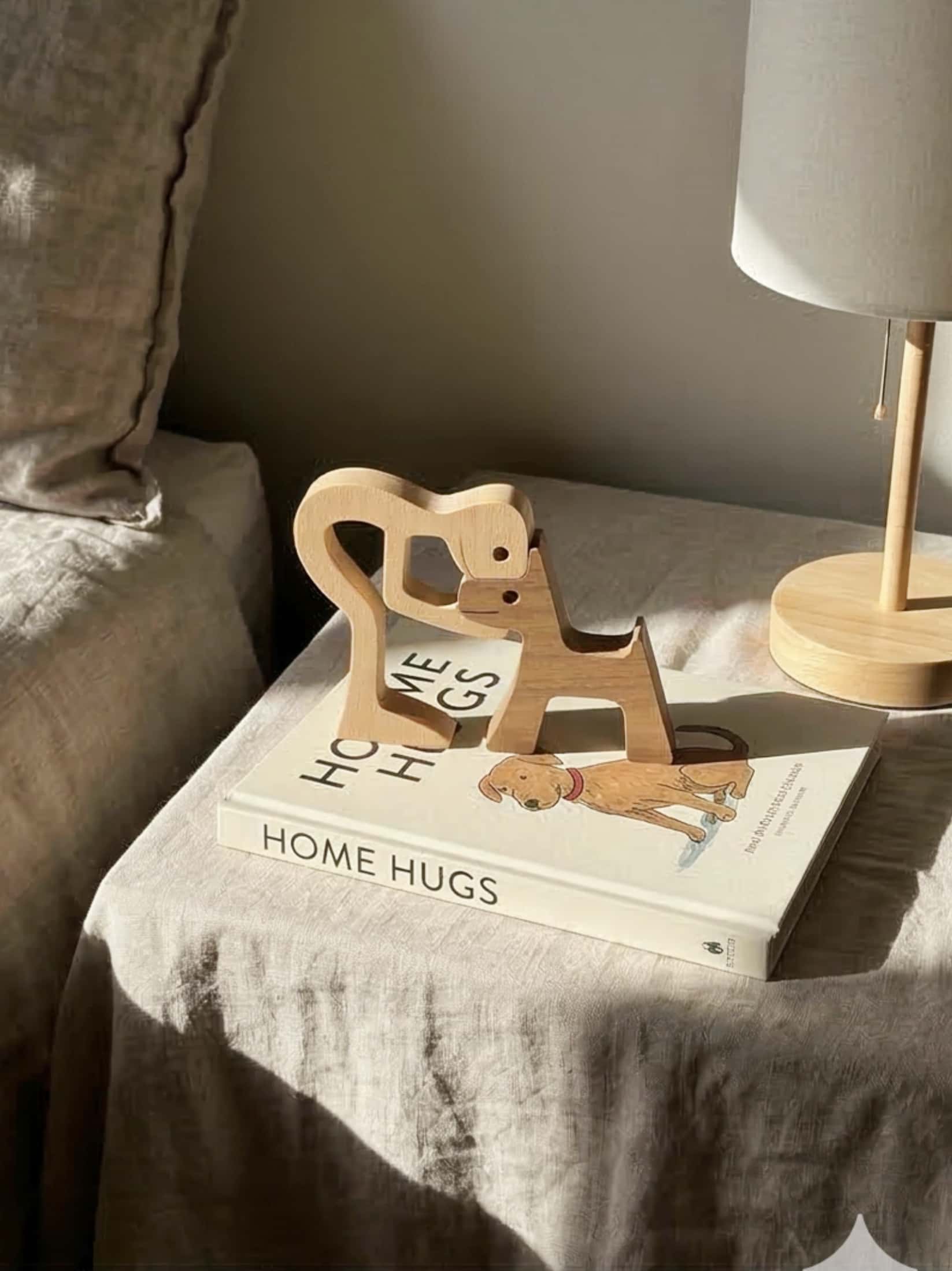 Wooden sculpture on a book titled 'Home Hugs' with a lamp in the background