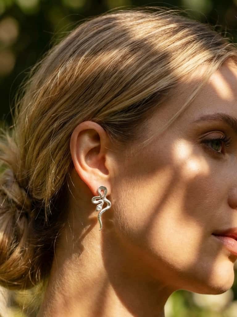 Close-up of a woman wearing Silver snake  earring with a blurred natural background