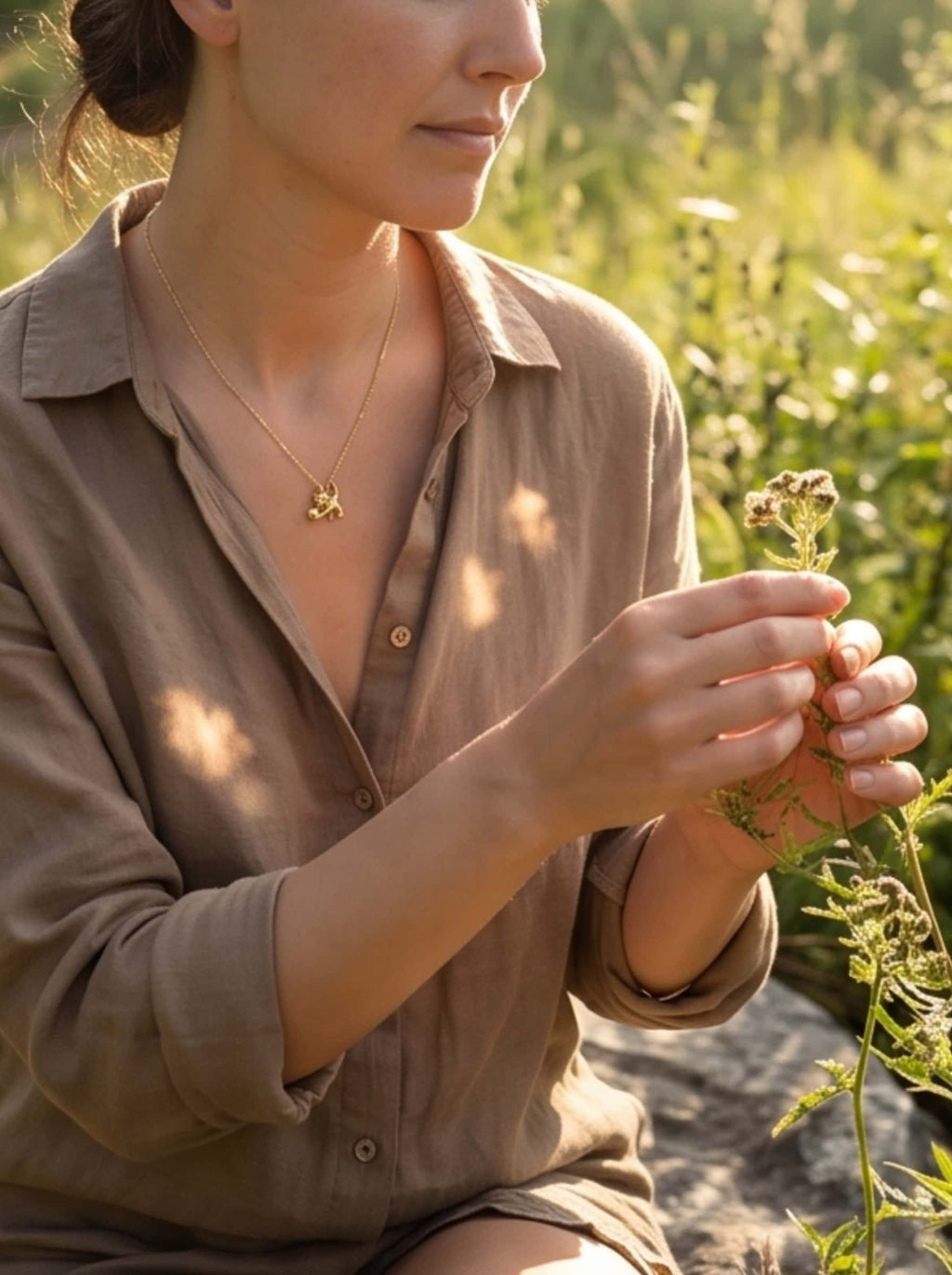 Atmospheric golden hour lifestyle photo of a woman wearing a minimalist gold cat necklace in nature