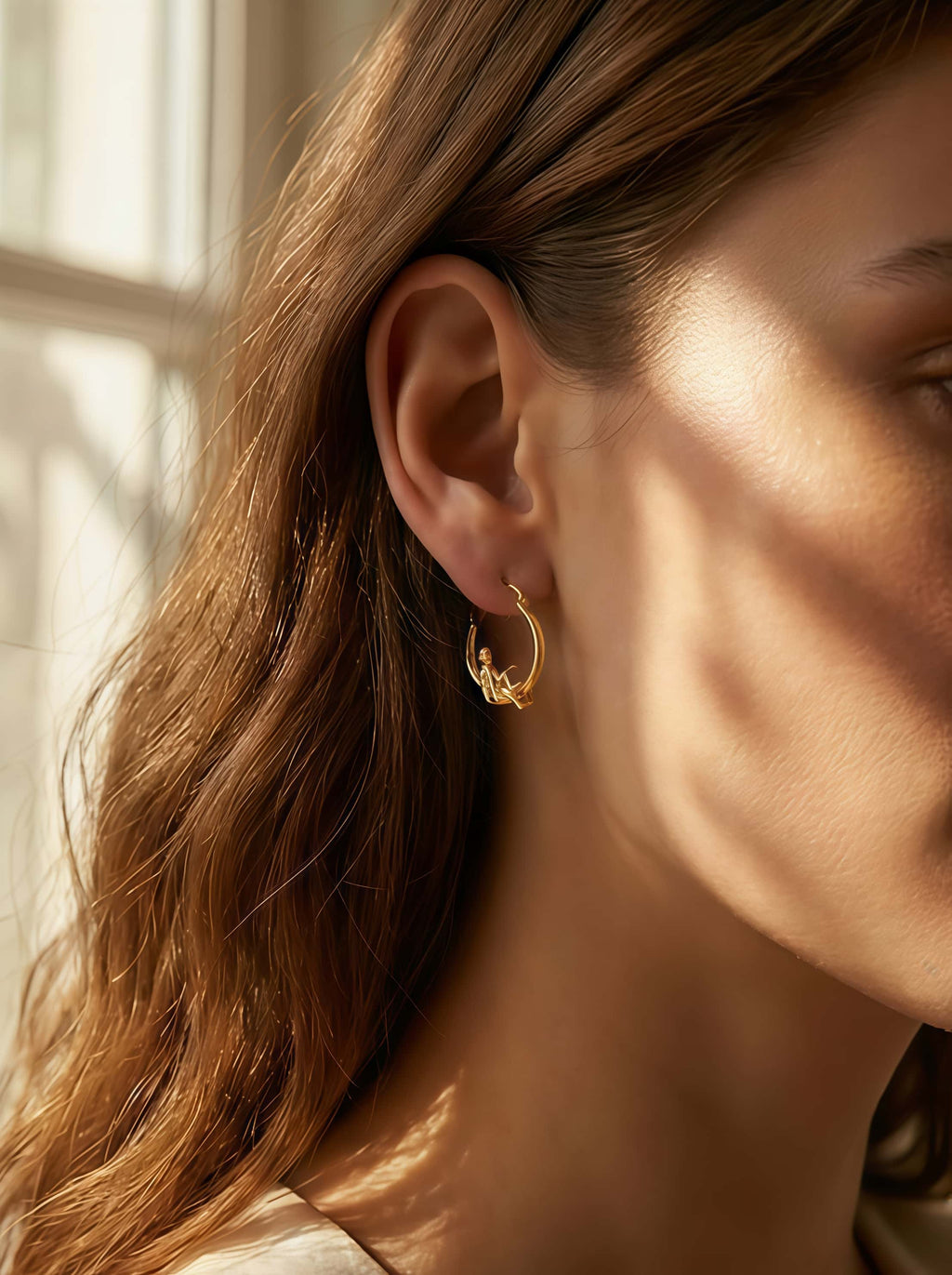 Close-up of a person wearing a gold hoop earring with soft lighting.