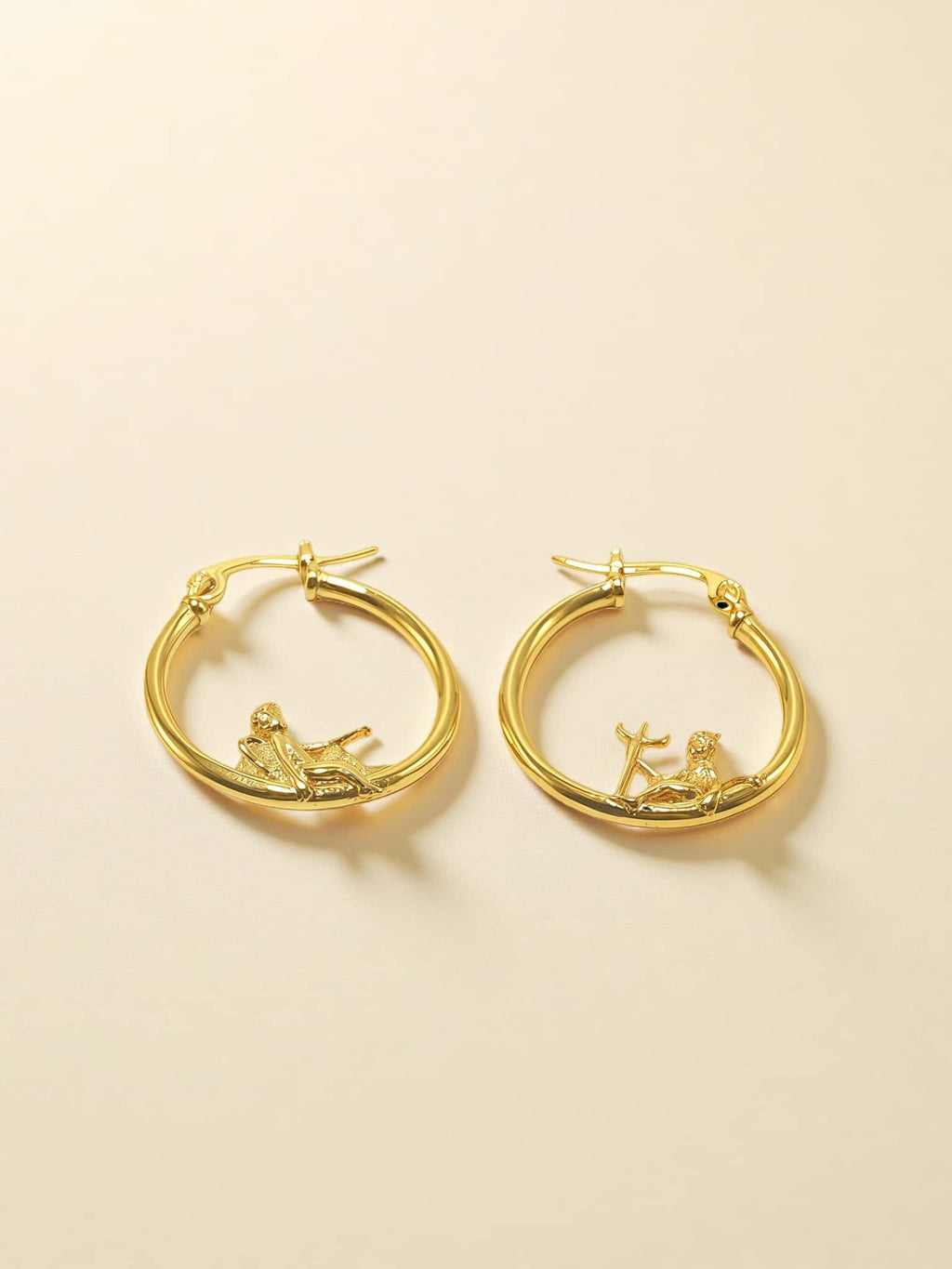 Gold hoop earrings with on a beige background