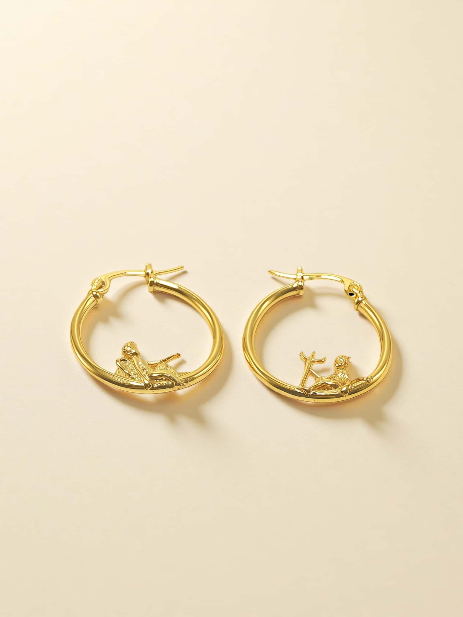 Gold hoop earrings with on a beige background
