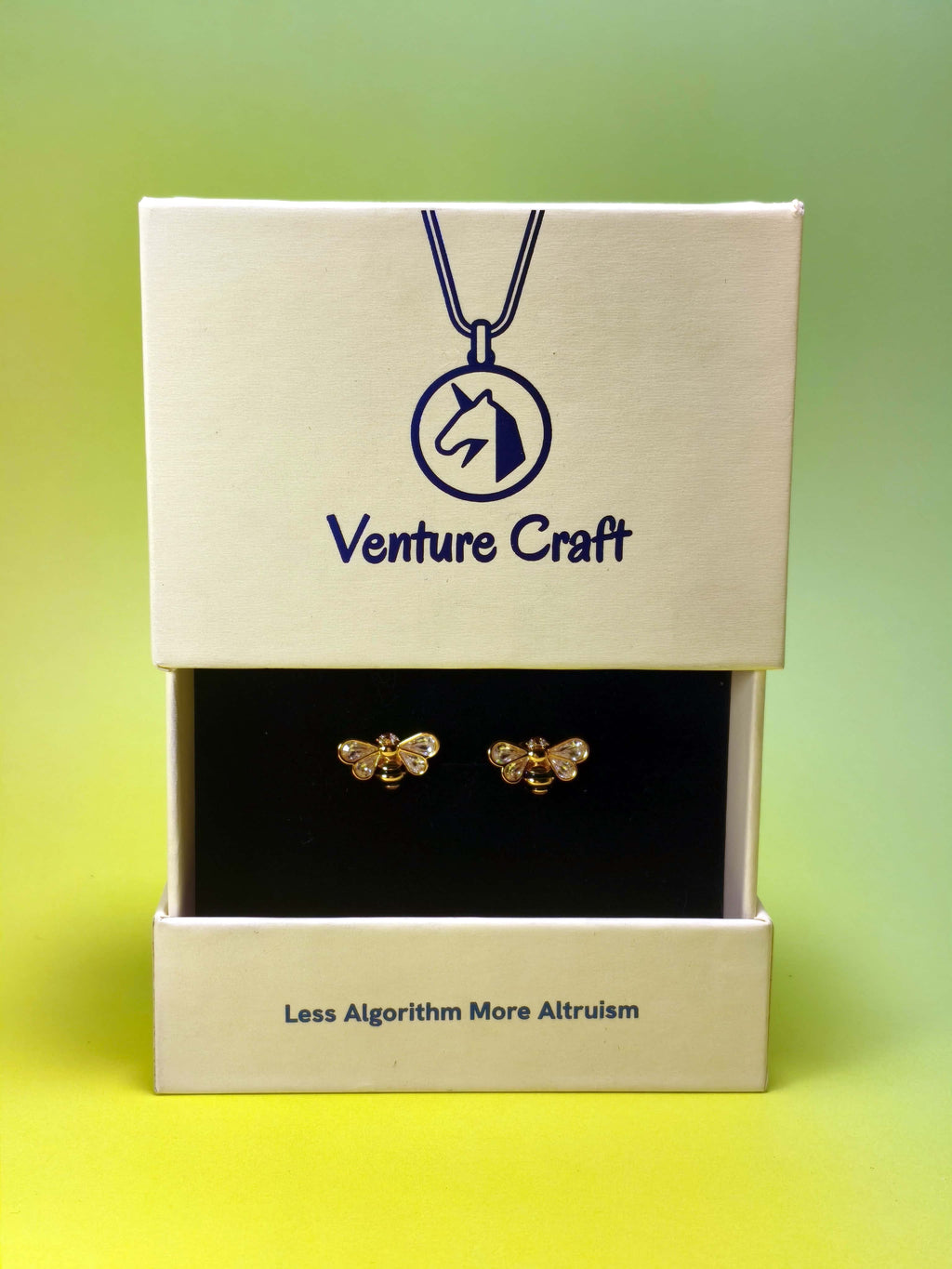 Gold bee earrings set in a Venture Craft box on a gradient background
