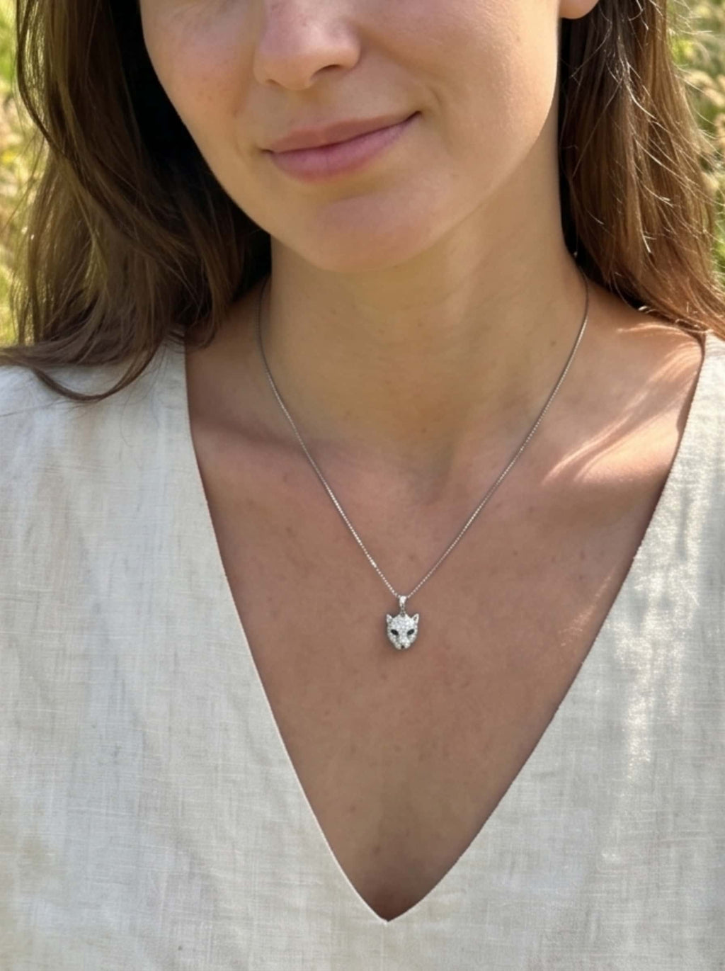 Elegant portrait of a smiling woman wearing the silver leopard necklace with a V-neck linen shirt, embodying a minimalist clean girl style