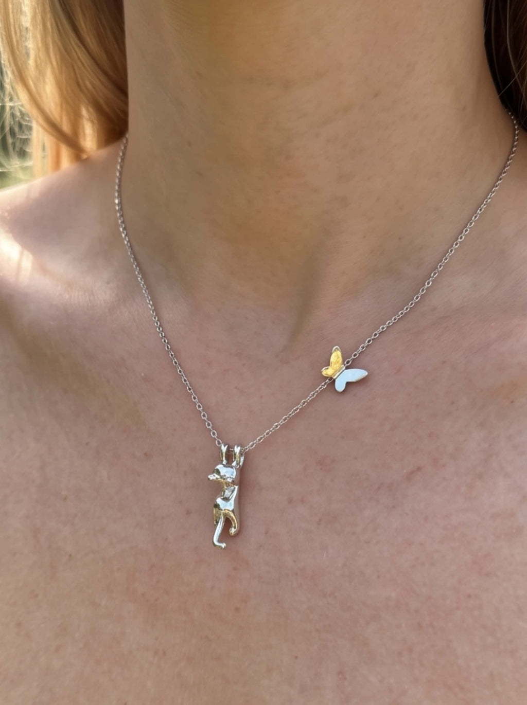 Close-up of a woman wearing the dainty cat pendant necklace, showing the detailed hanging cat charm and butterfly detail on the collarbone