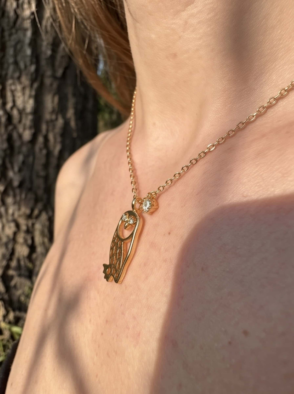 Side angle close-up of the 18K gold owl pendant resting on the collarbone, highlighting the polished finish and dimensional silhouette