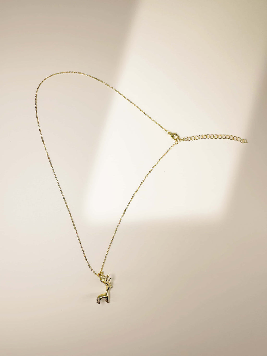 Full view of the 18K gold deer necklace showing the fine link chain and lobster clasp
