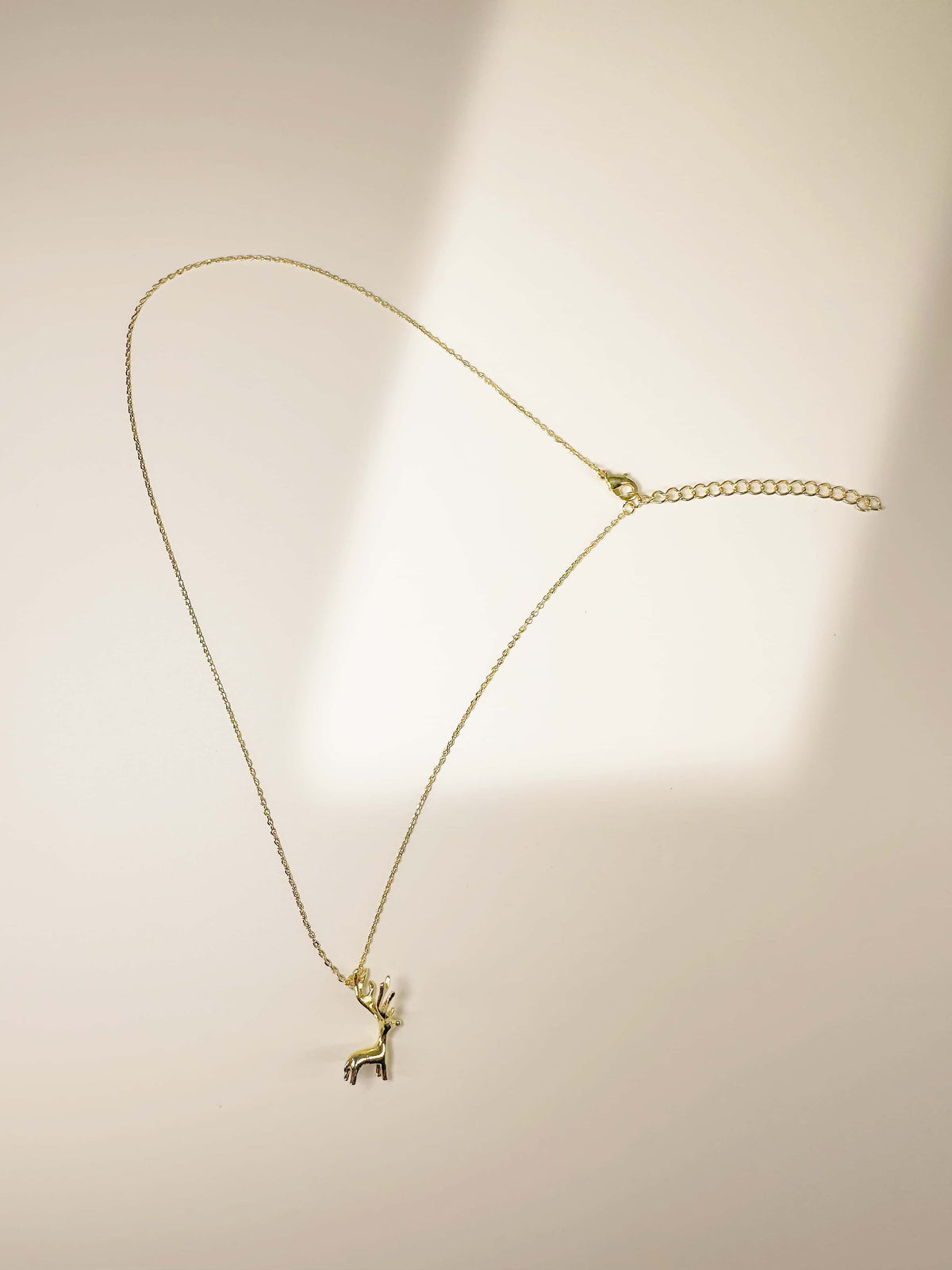 Full view of the 18K gold deer necklace showing the fine link chain and lobster clasp