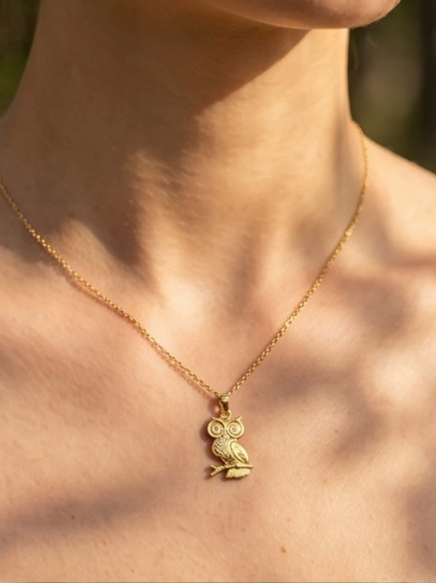 Detailed view of the 18K gold owl pendant necklace resting on a model's collarbone, highlighting the elegant dapple shadow effect