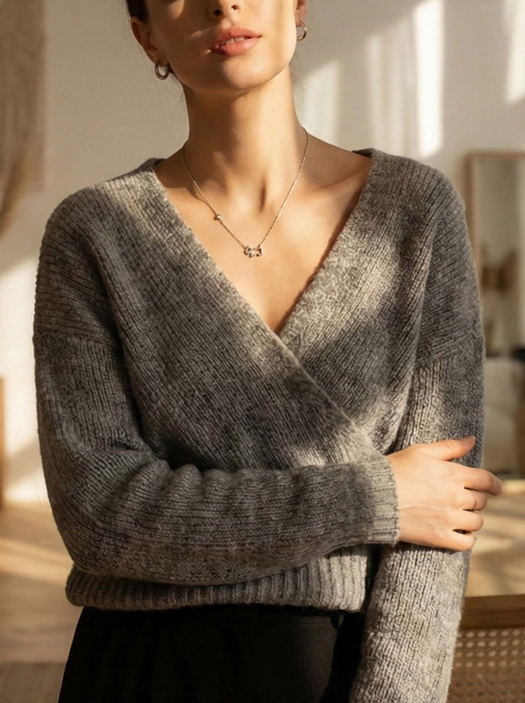 Lifestyle portrait of a woman in a cozy grey wrap sweater styling the silver dog pendant necklace for an effortless, everyday look.