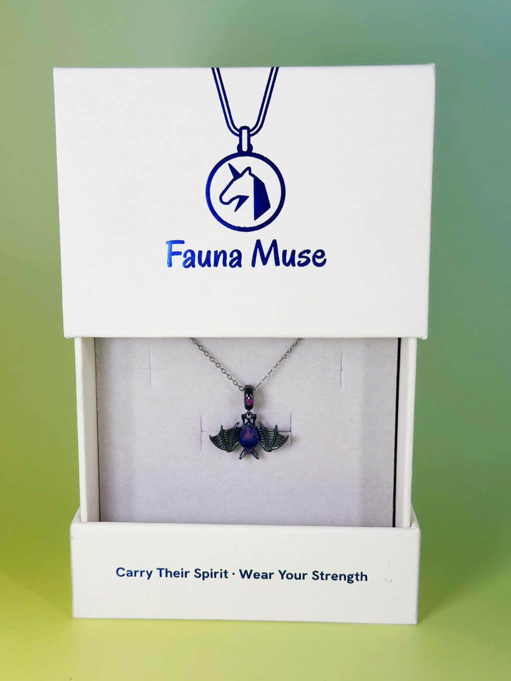 Fauna Muse black bat pendant necklace with purple crystal displayed inside a white branded gift box