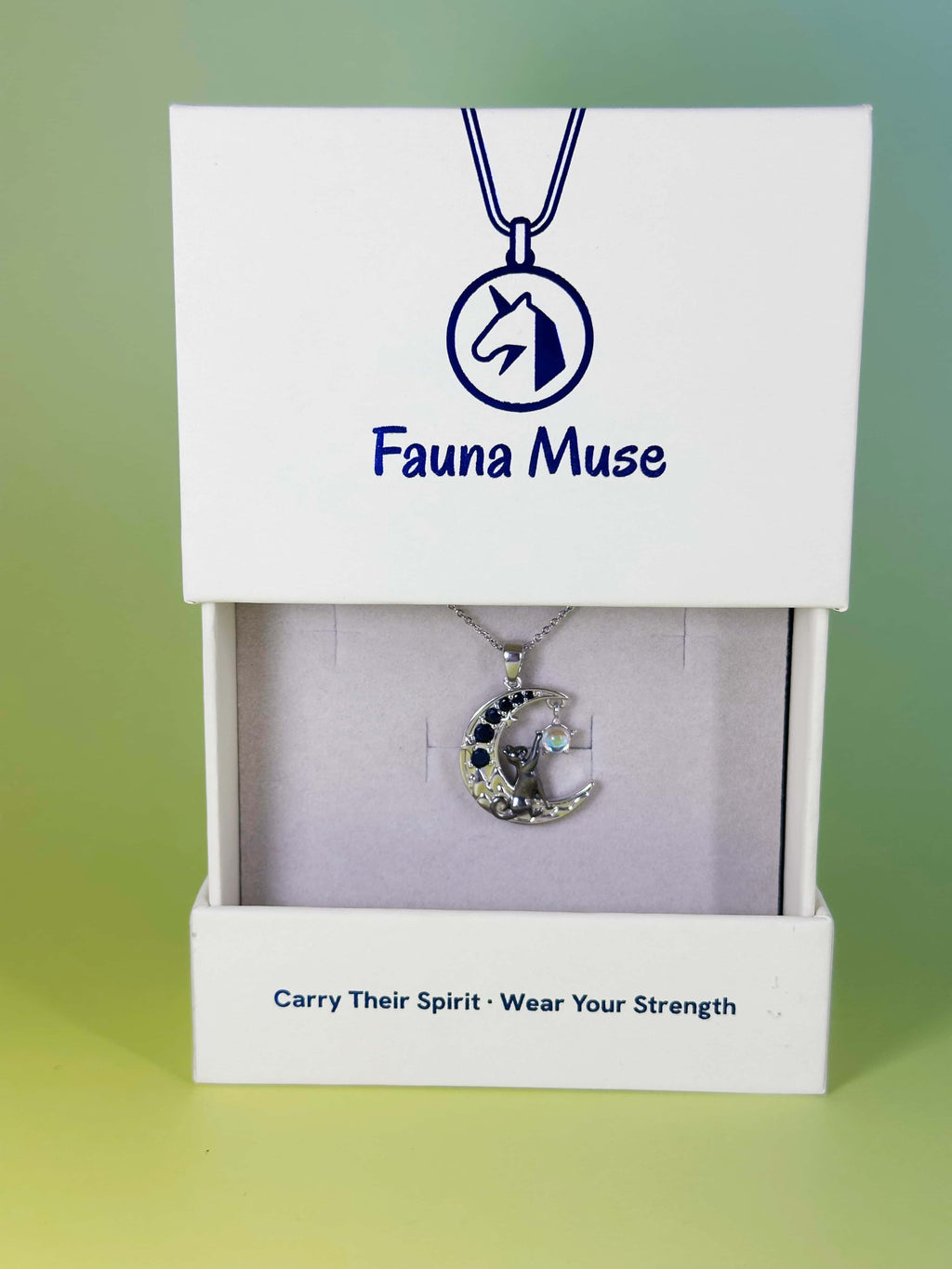 Fauna Muse silver crescent moon pendant necklace featuring a black cat and dark blue gemstones, displayed inside a white branded gift box