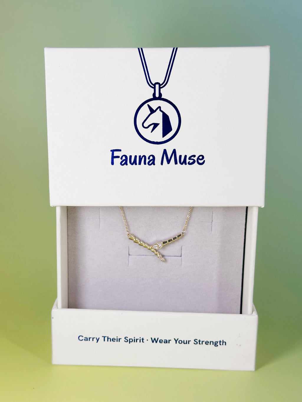 Fauna Muse gold curved snake bar necklace with crystal accents displayed inside a white branded gift box