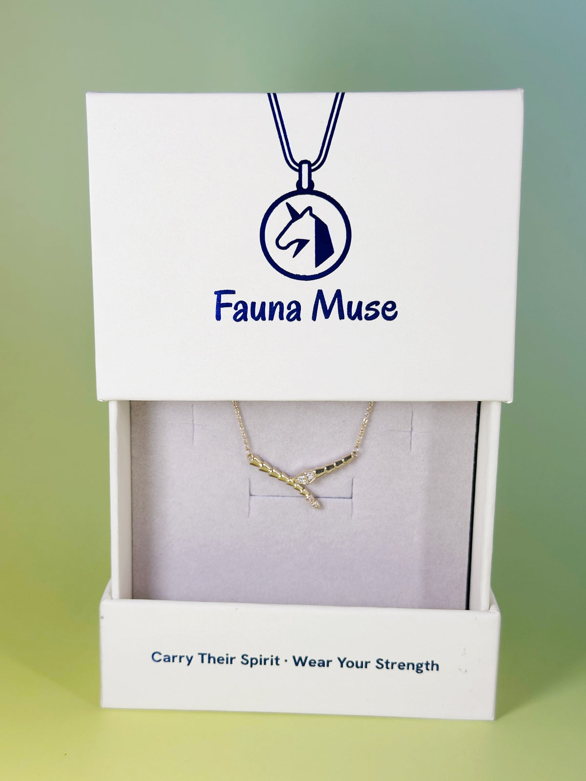Fauna Muse gold curved snake bar necklace with crystal accents displayed inside a white branded gift box