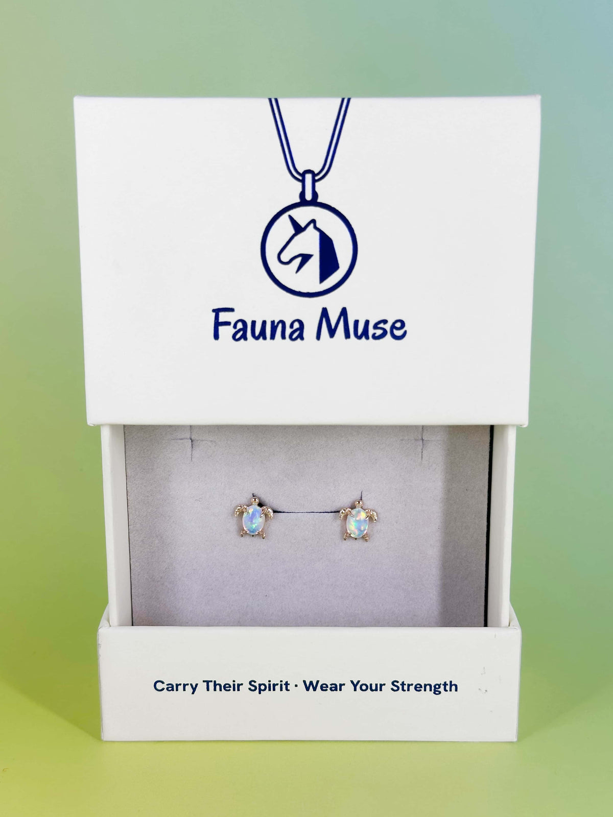Fauna Muse gold sea turtle stud earrings with iridescent opal shells displayed in a white branded jewelry gift box
