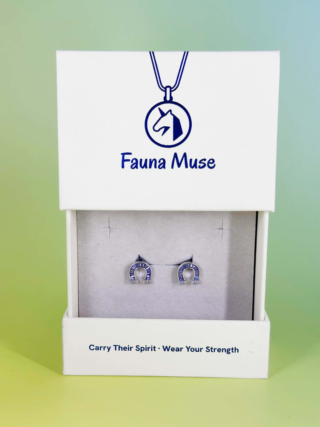 Fauna Muse silver horseshoe stud earrings with purple crystal baguettes displayed in a white branded jewelry gift box