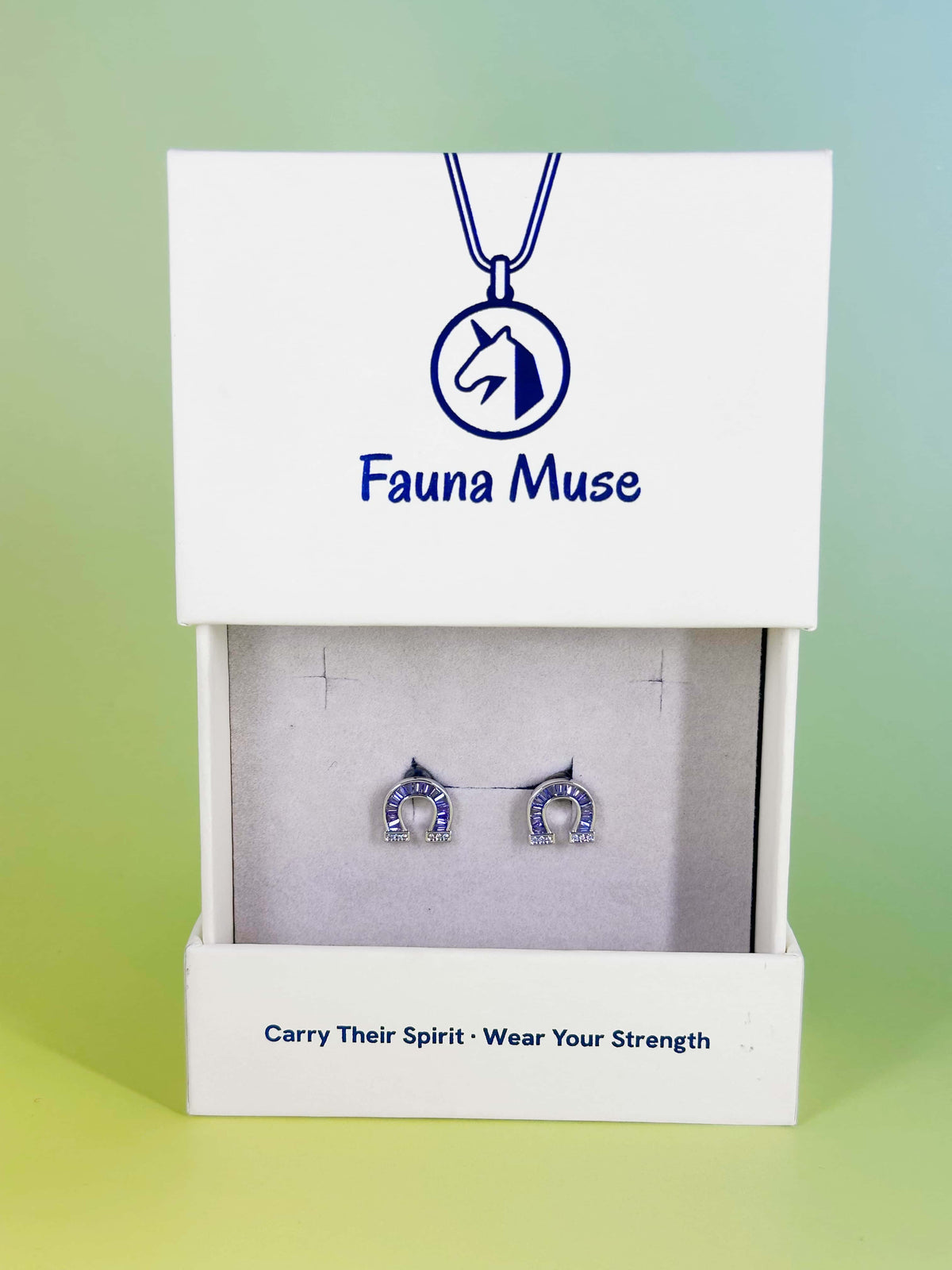 Fauna Muse silver horseshoe stud earrings with purple crystal baguettes displayed in a white branded jewelry gift box