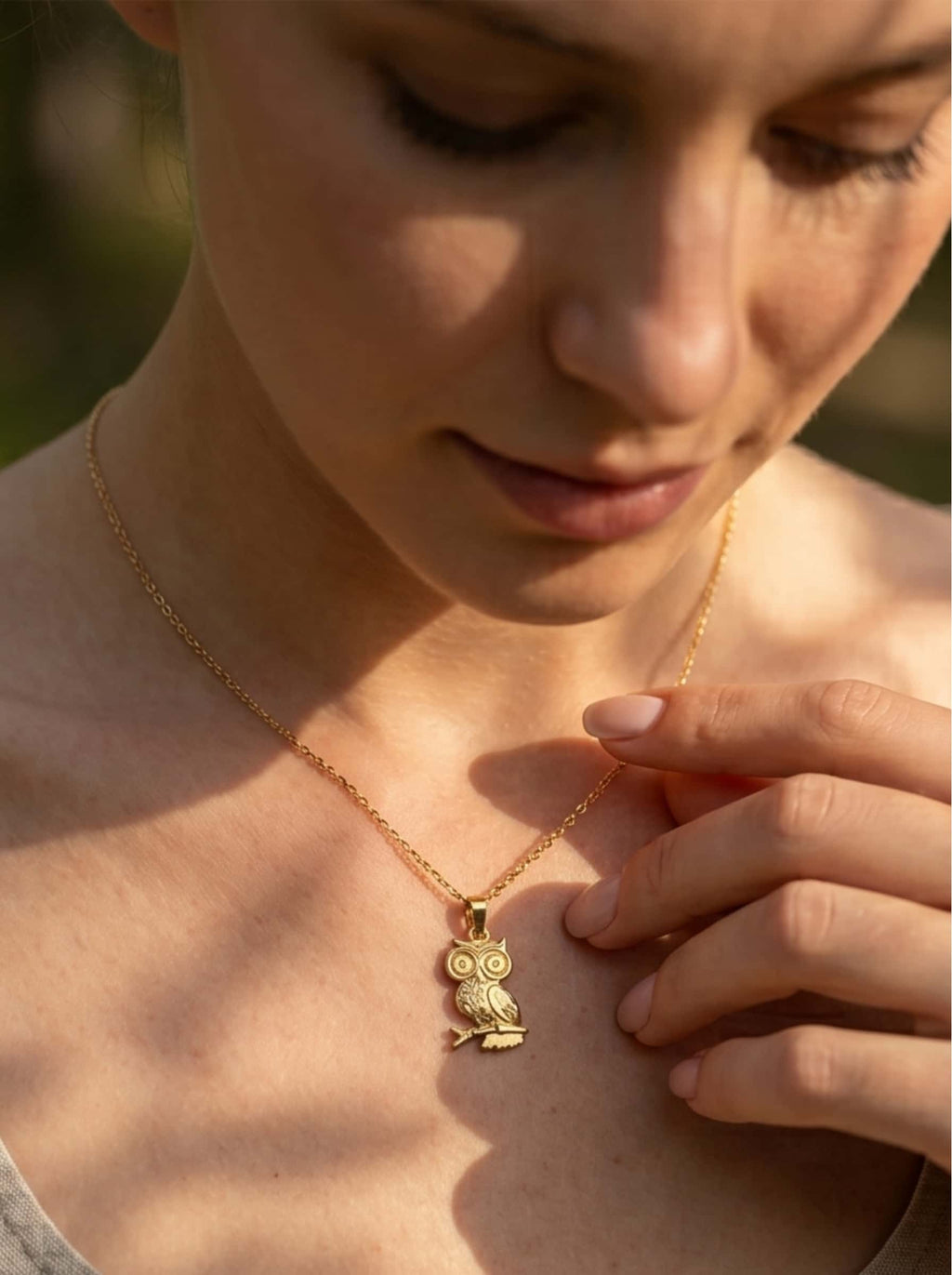 Close-up of a female model wearing the textured gold owl pendant necklace, showcasing the intricate craftsmanship under soft natural sunlight