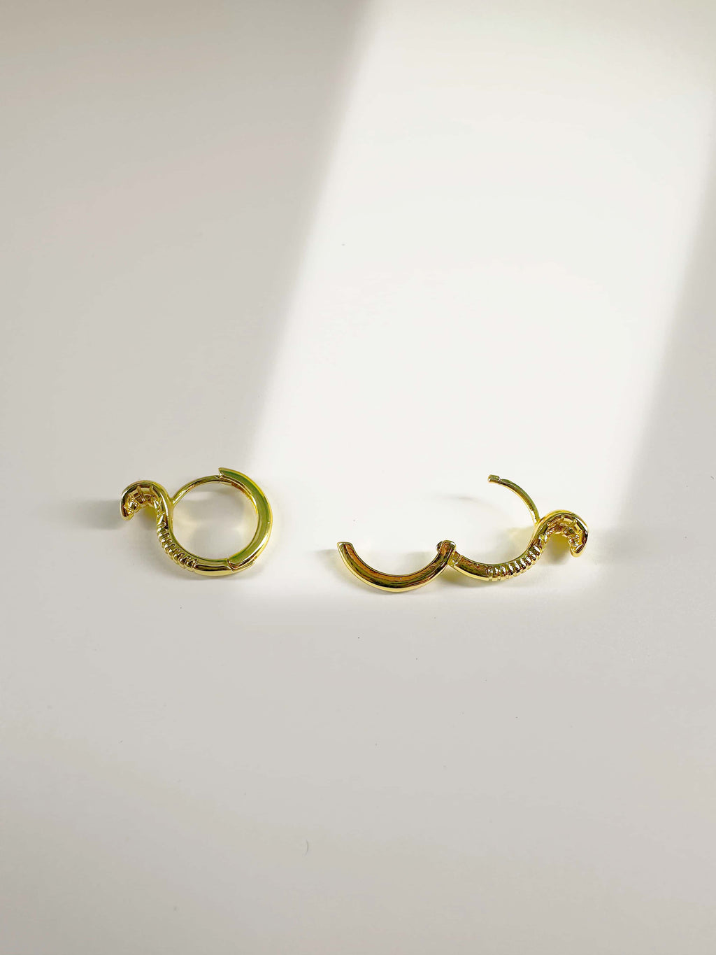 Open and closed view of 18K gold snake earrings showing the secure hinged huggie hoop clasp