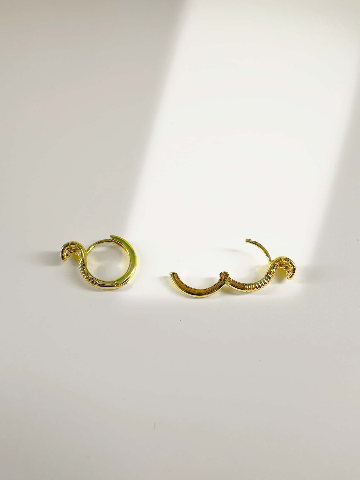 Open and closed view of 18K gold snake earrings showing the secure hinged huggie hoop clasp