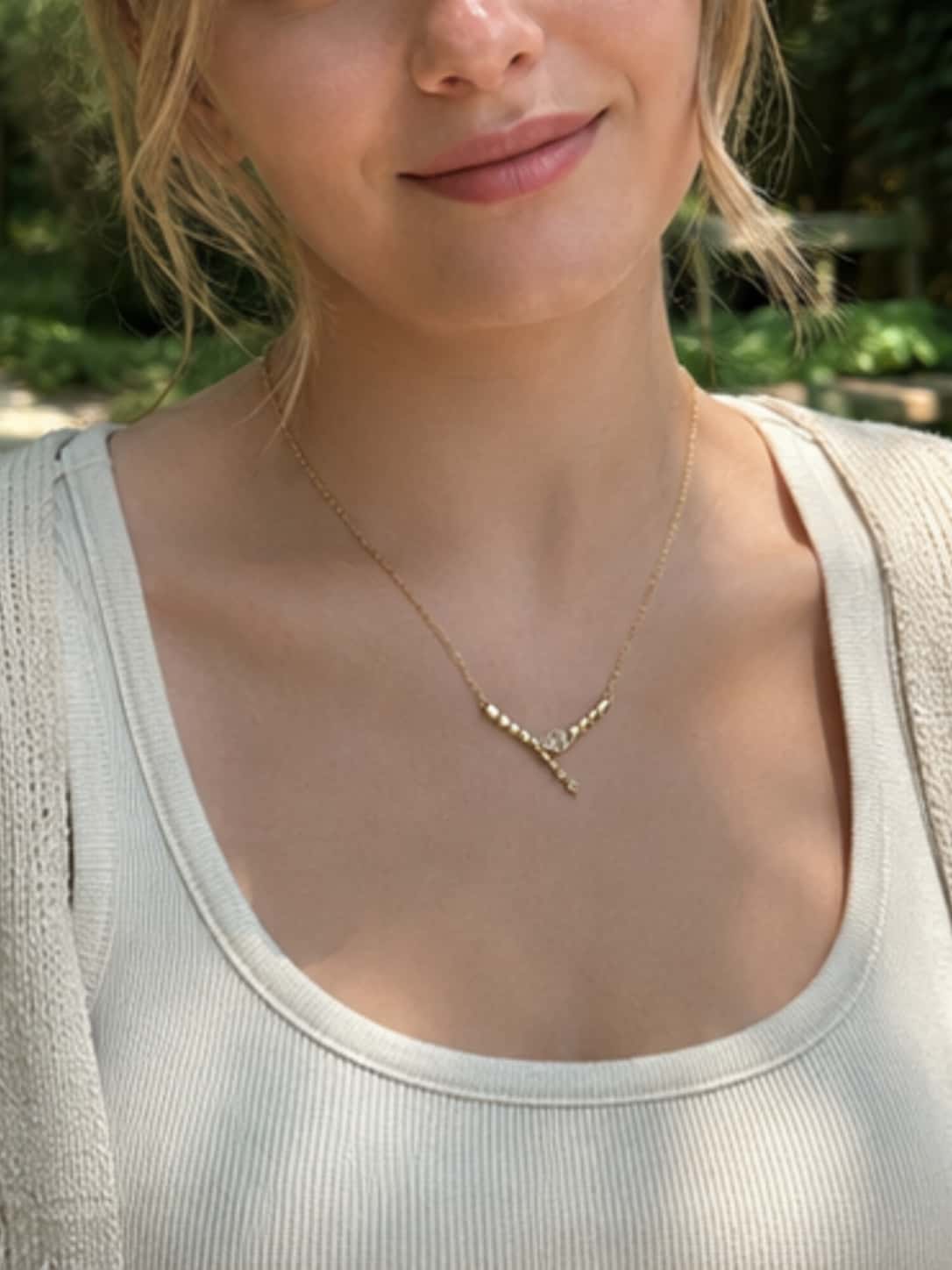 Close-up of a female model wearing the dainty gold snake necklace paired with a casual ribbed top, showcasing its elegant drop on the neckline