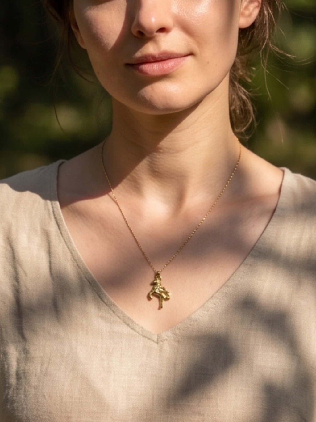 Front lifestyle view of the elegant gold unicorn necklace resting on a woman's chest with natural lighting