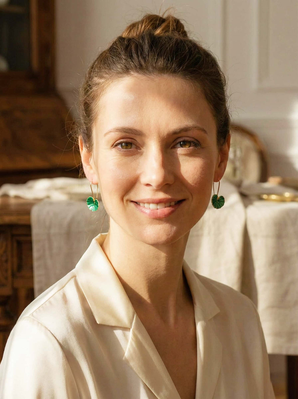 Woman wearing green earrings in a casual indoor setting