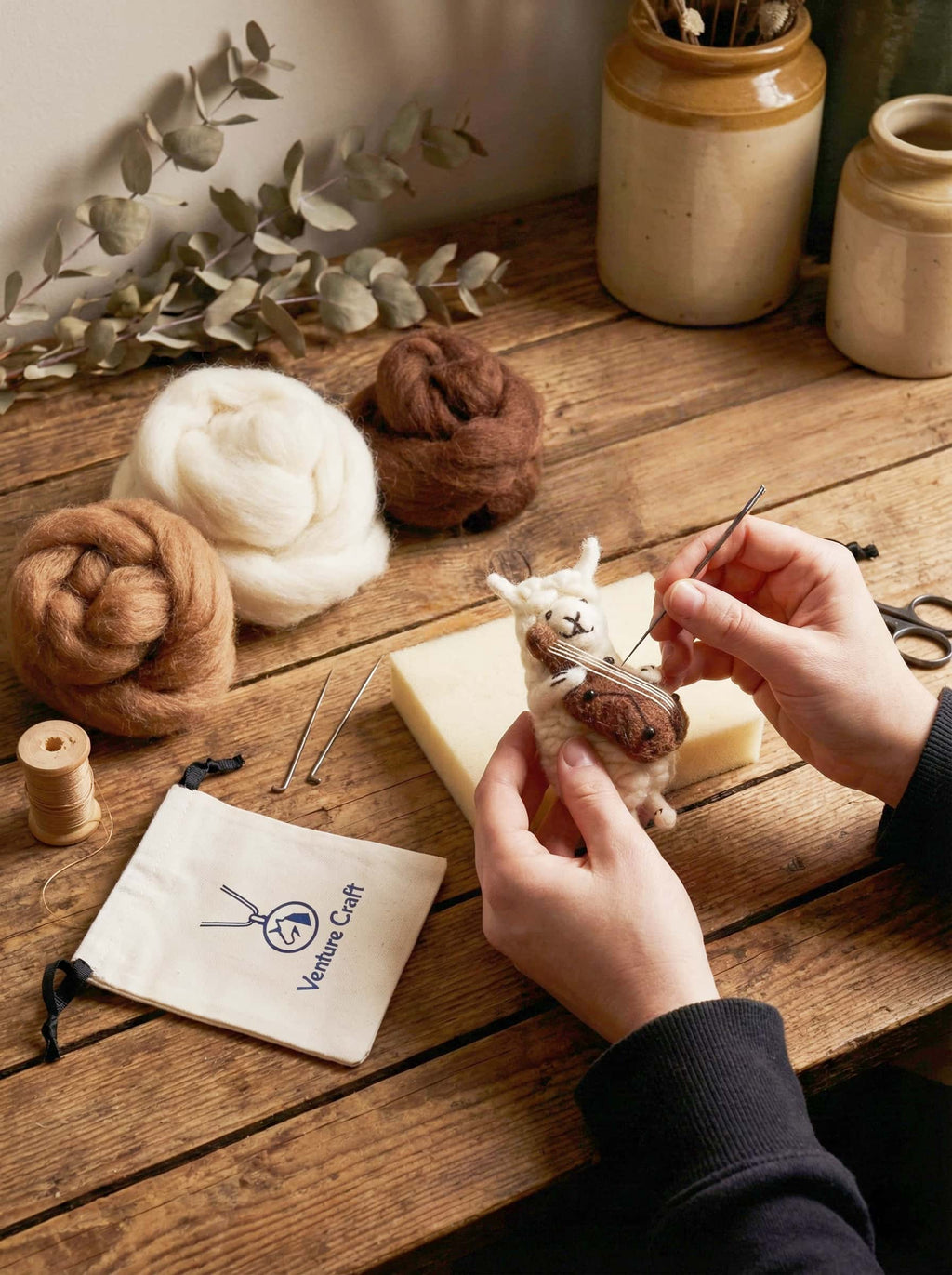 Person knitting with yarn and knitting needles on wool felt sheep with violin