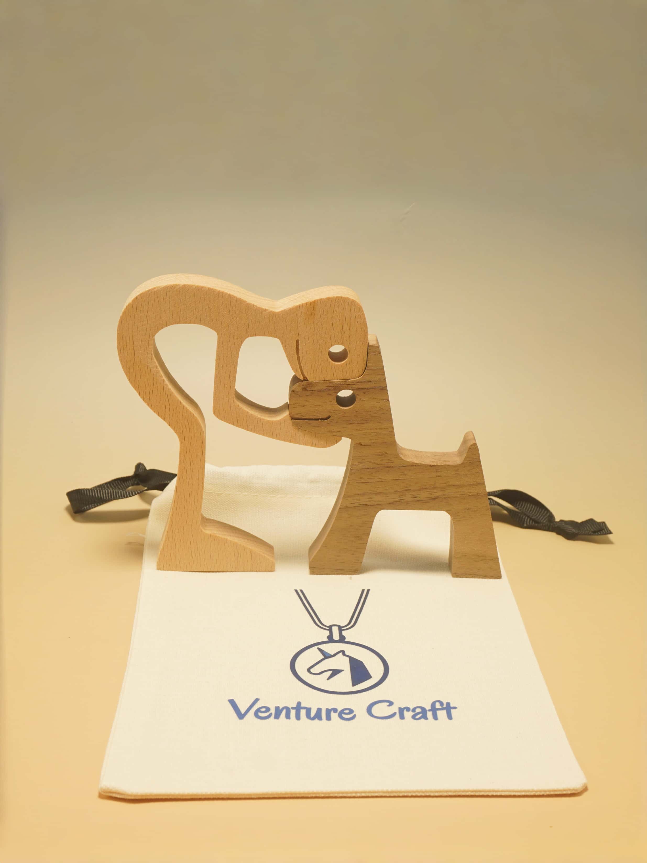 man &dog sculpture from wood on a stand with 'Venture Craft' branding on a beige background
