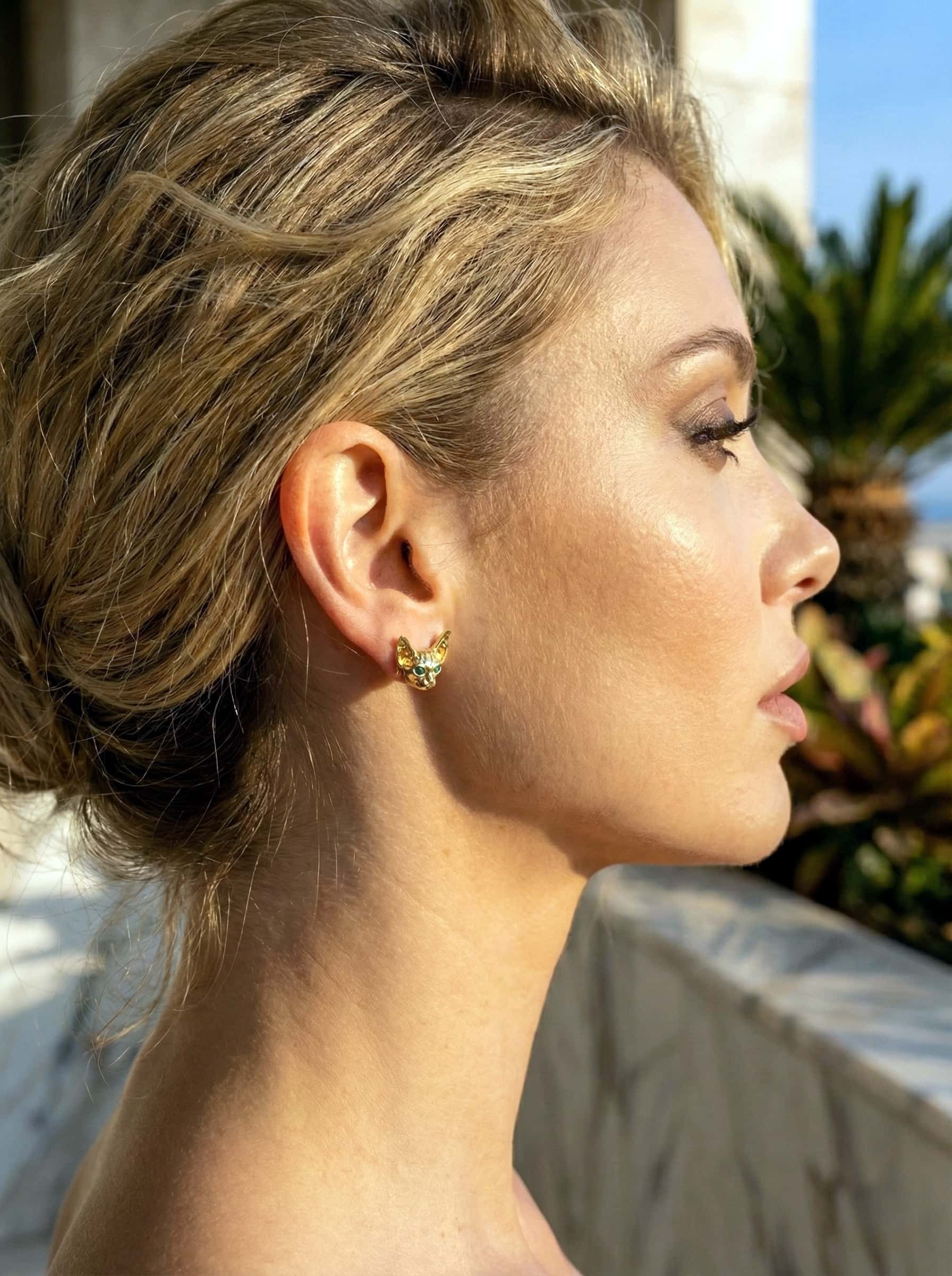 Close-up of a woman's profile with a sphinx-cat earrings