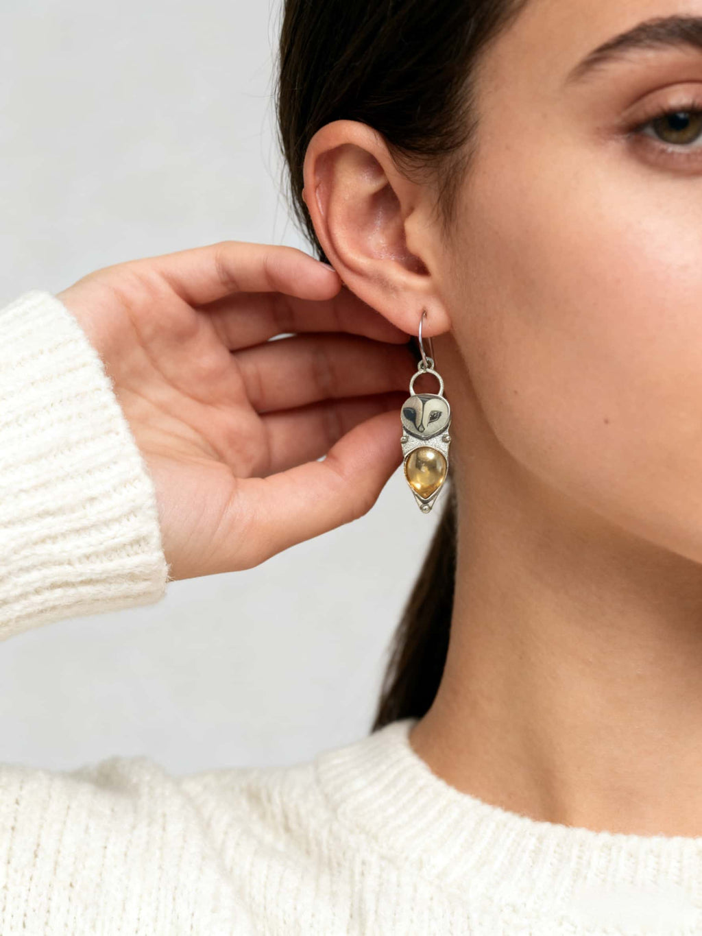 Close-up of a person wearing a owl earrings