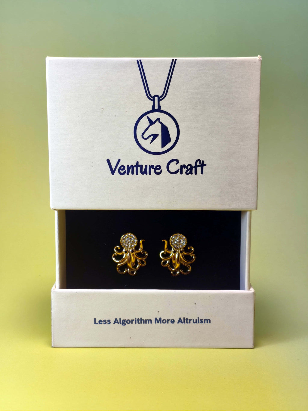Gold octopus earrings in a Venture Craft gift box on a gradient background