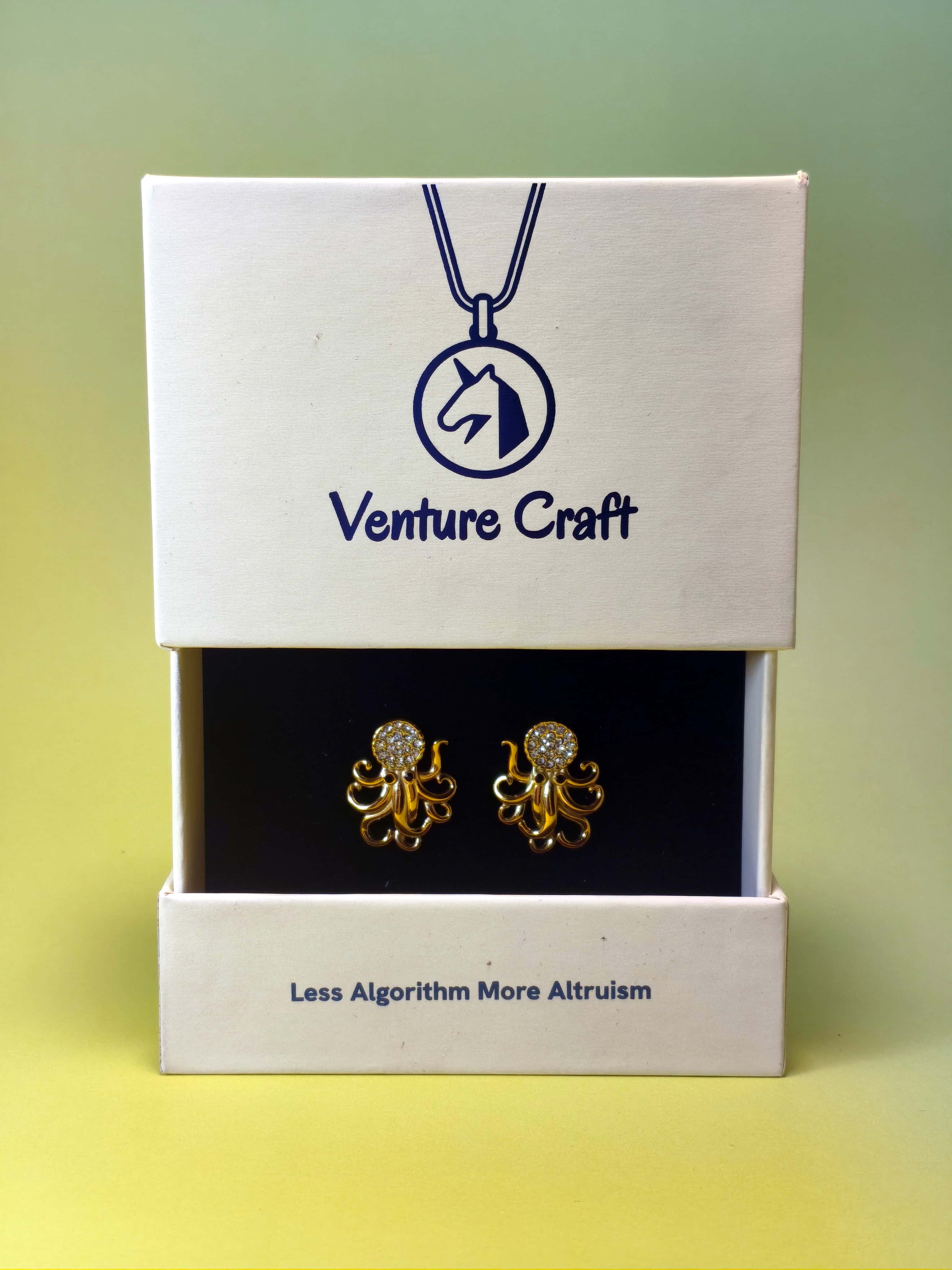 Gold octopus earrings in a Venture Craft gift box on a gradient background