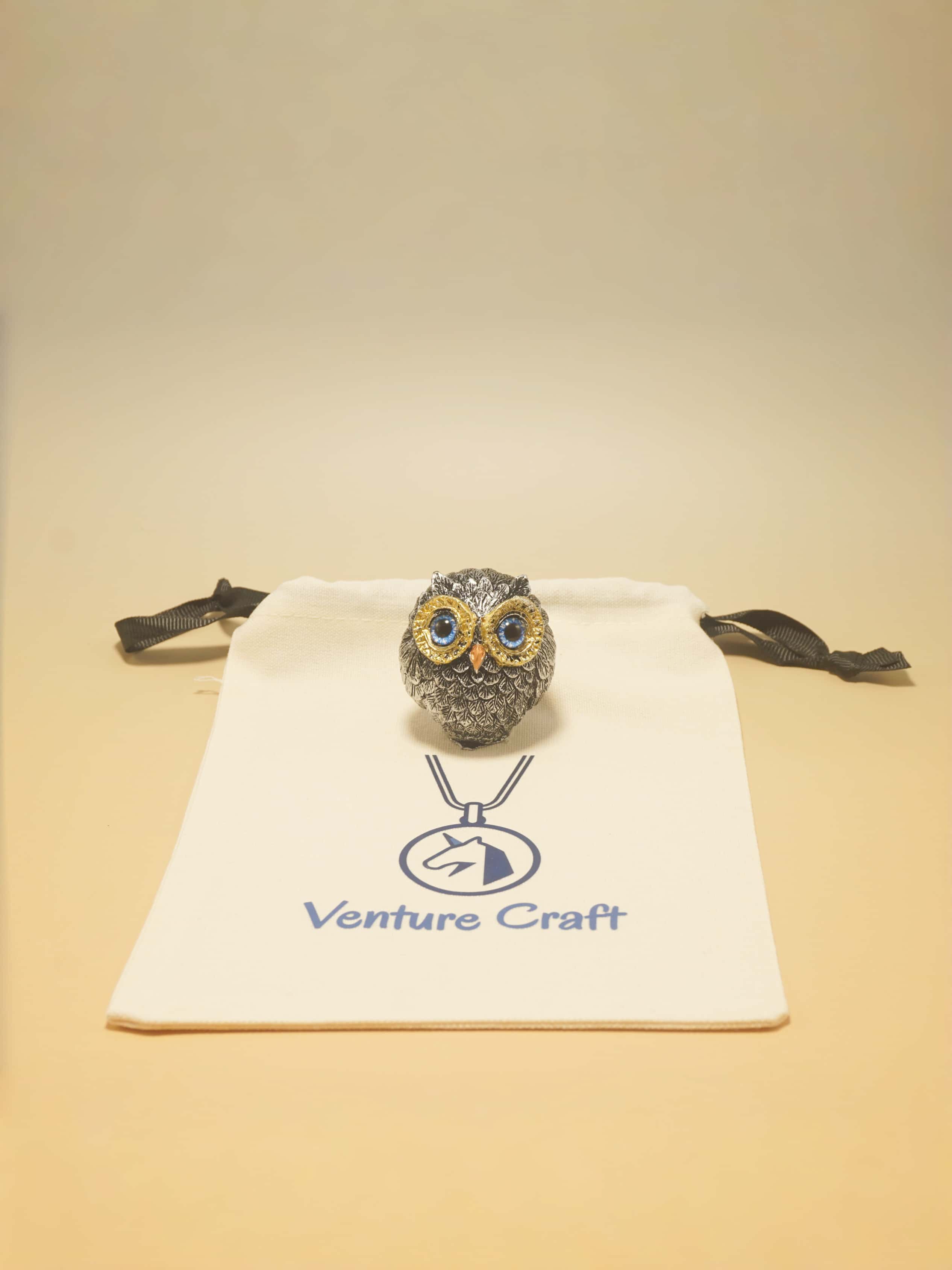 Owl-shaped sculpture on a Venture Craft pouch with a beige background
